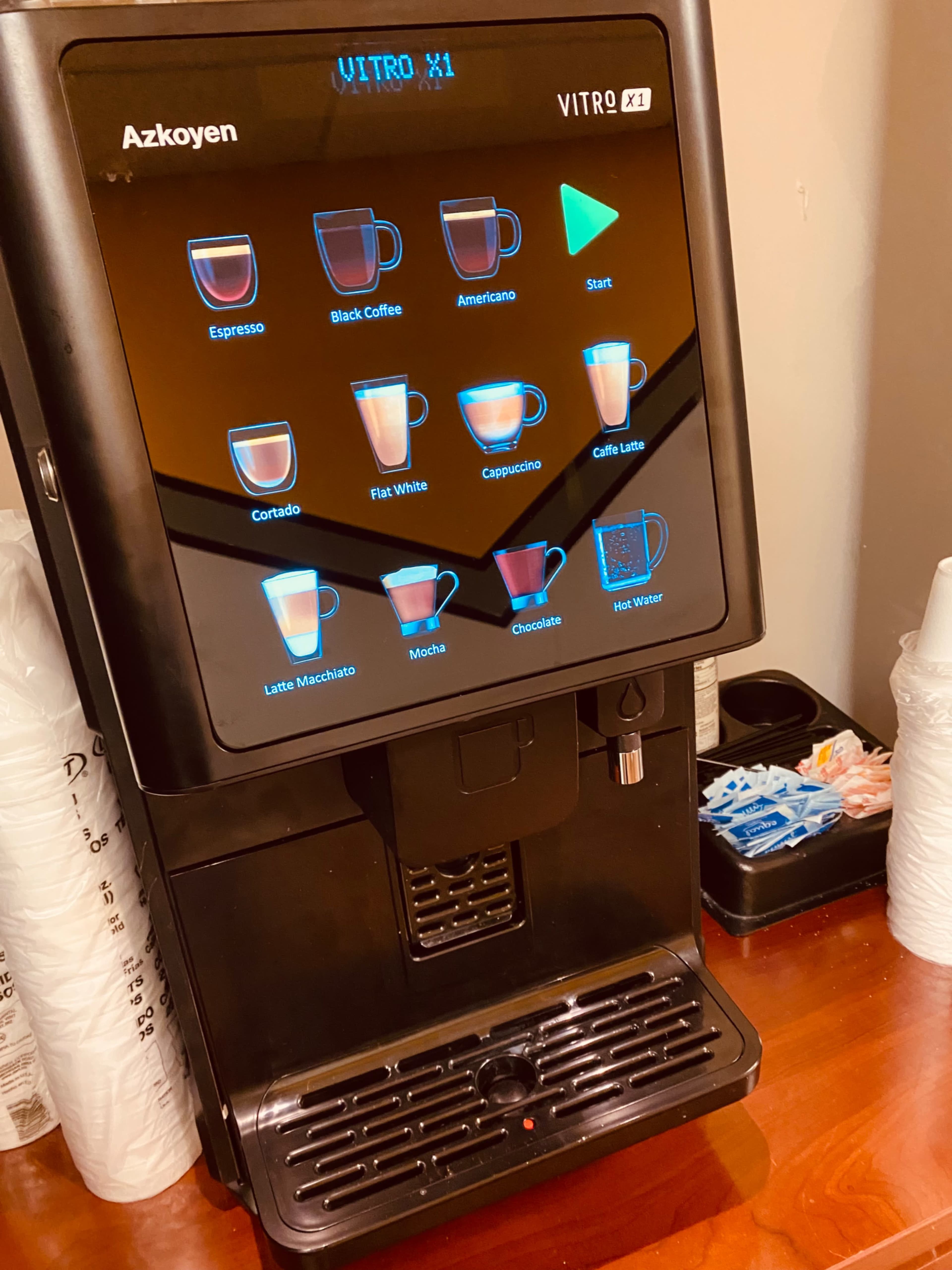 A self-service coffee machine with various drink options displayed on a touchscreen interface.