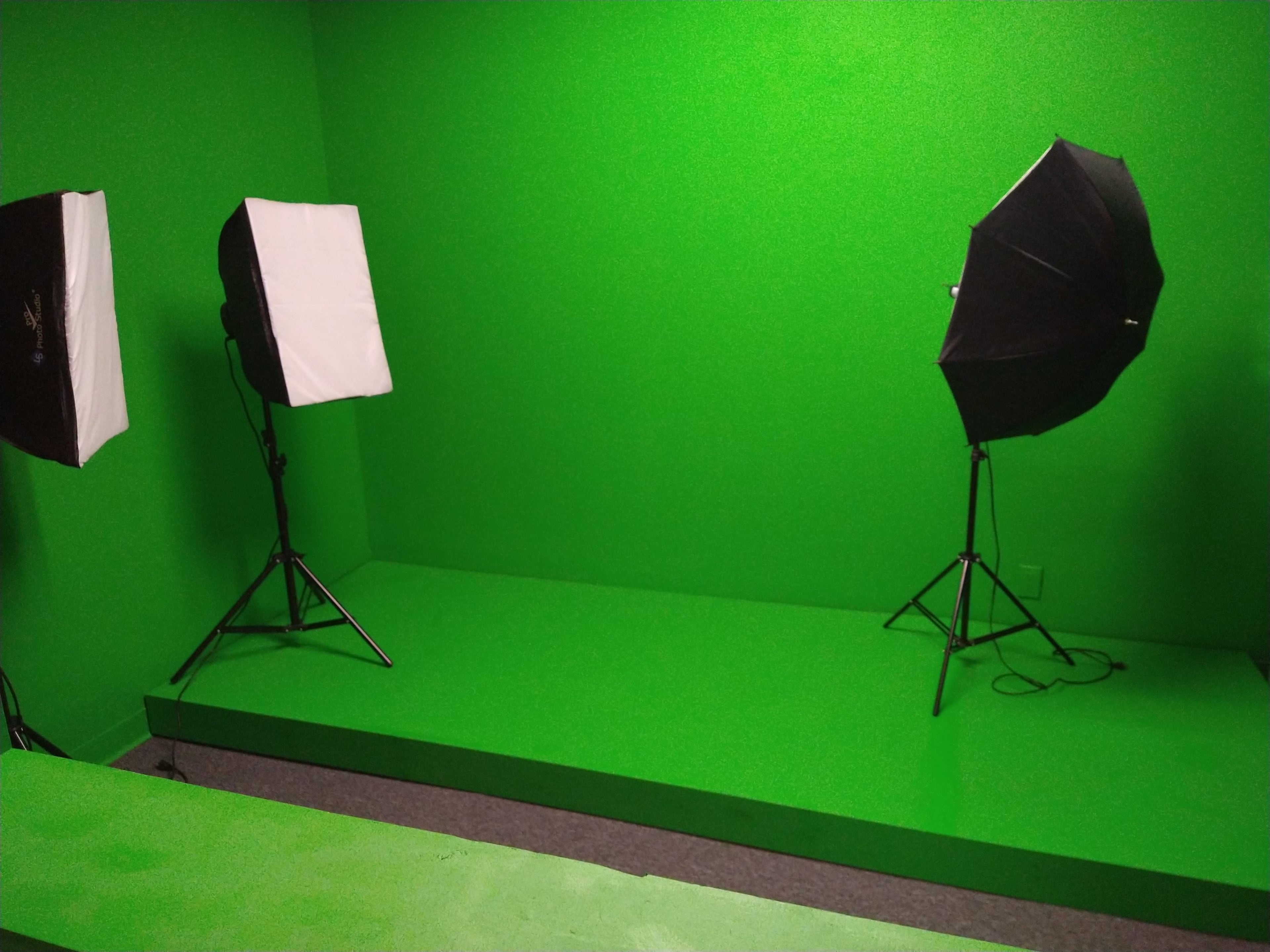 The image shows a green screen studio equipped with two light stands.