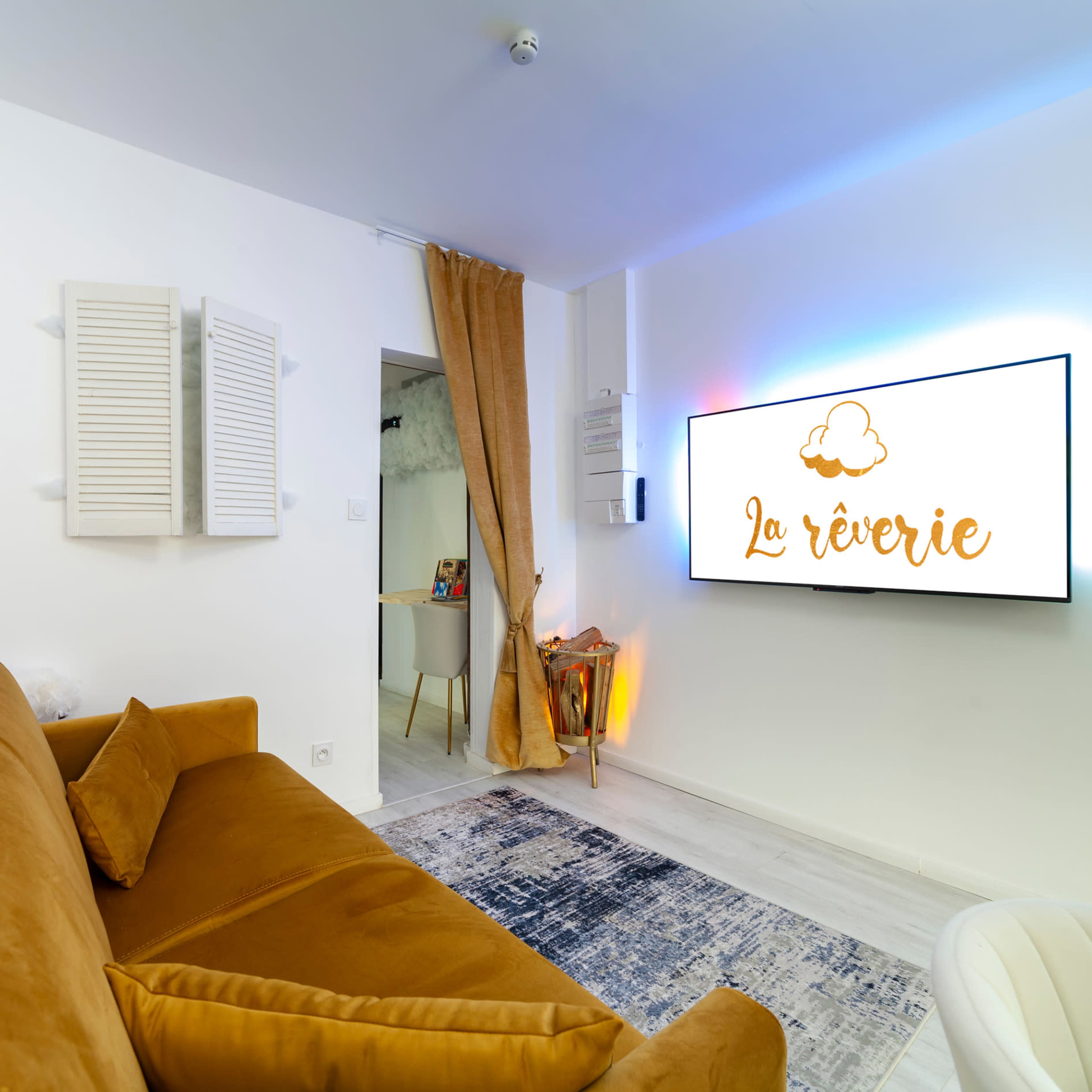 The image shows a cozy room with a brown sofa, a modern television displaying the words "La rêverie," and light-colored walls.