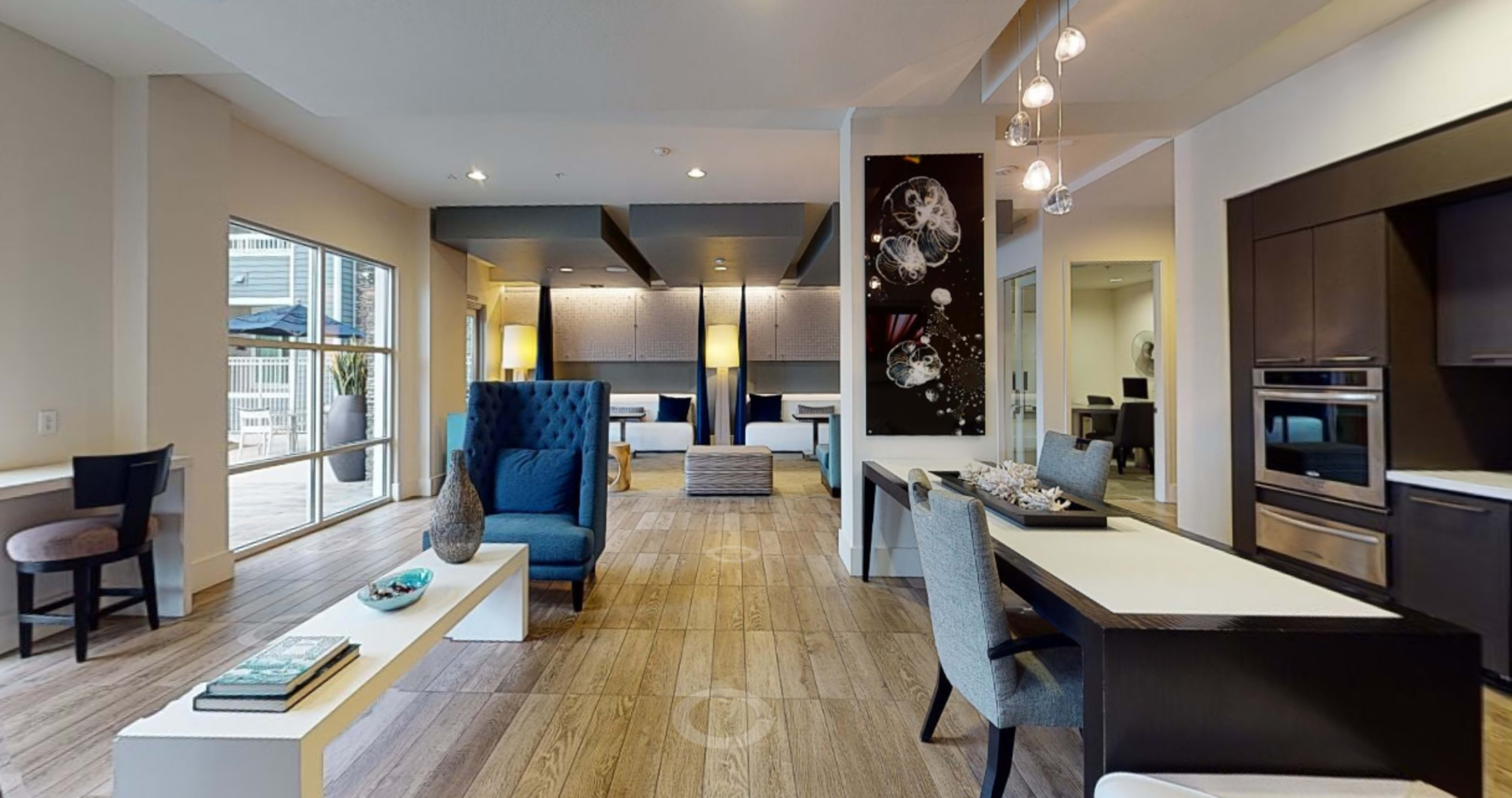 A modern interior space featuring a lounge area with seating, a dining table, and kitchen amenities.