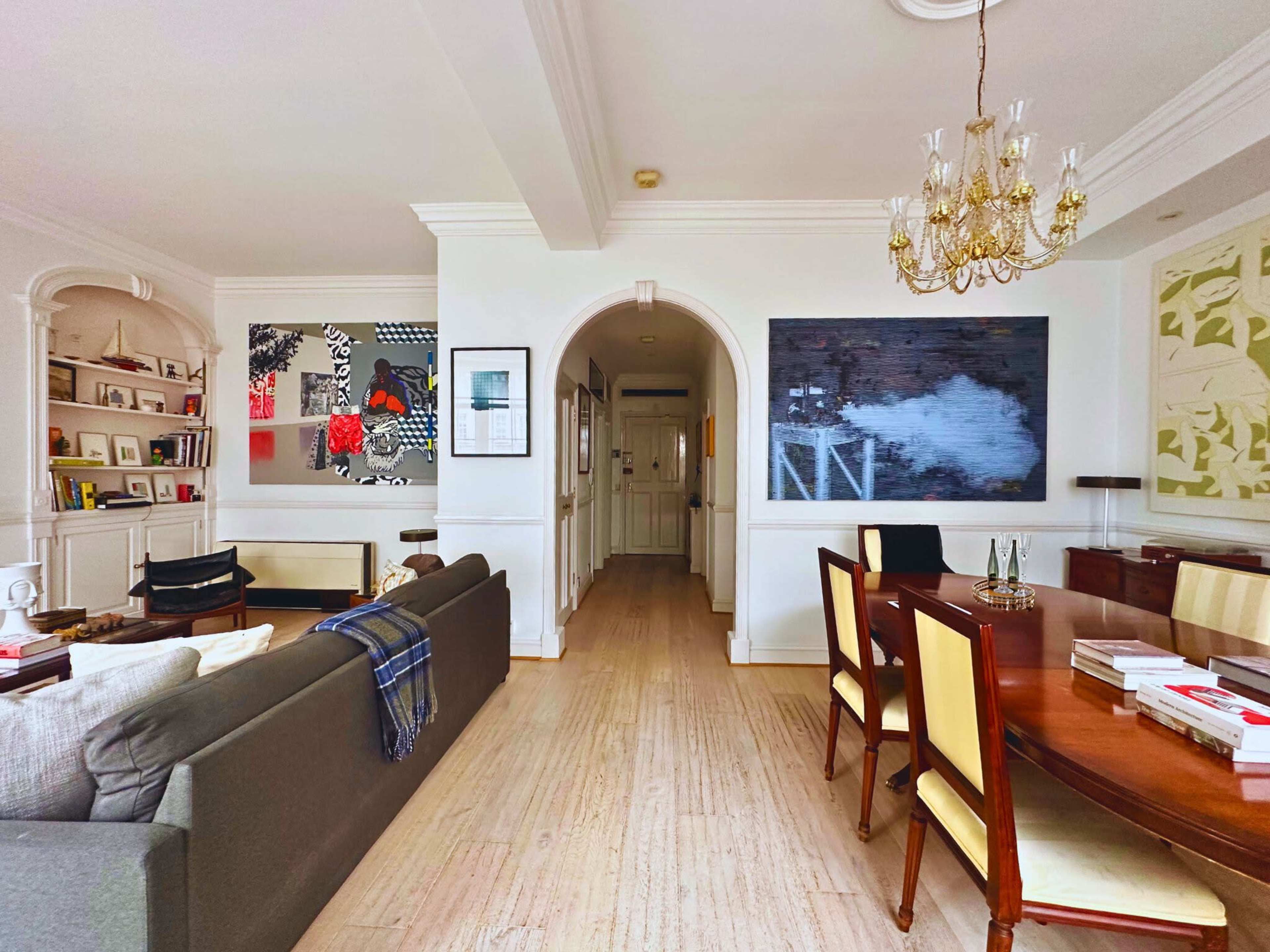 A well-lit living space featuring a seating area, a dining table, and artwork on the walls.