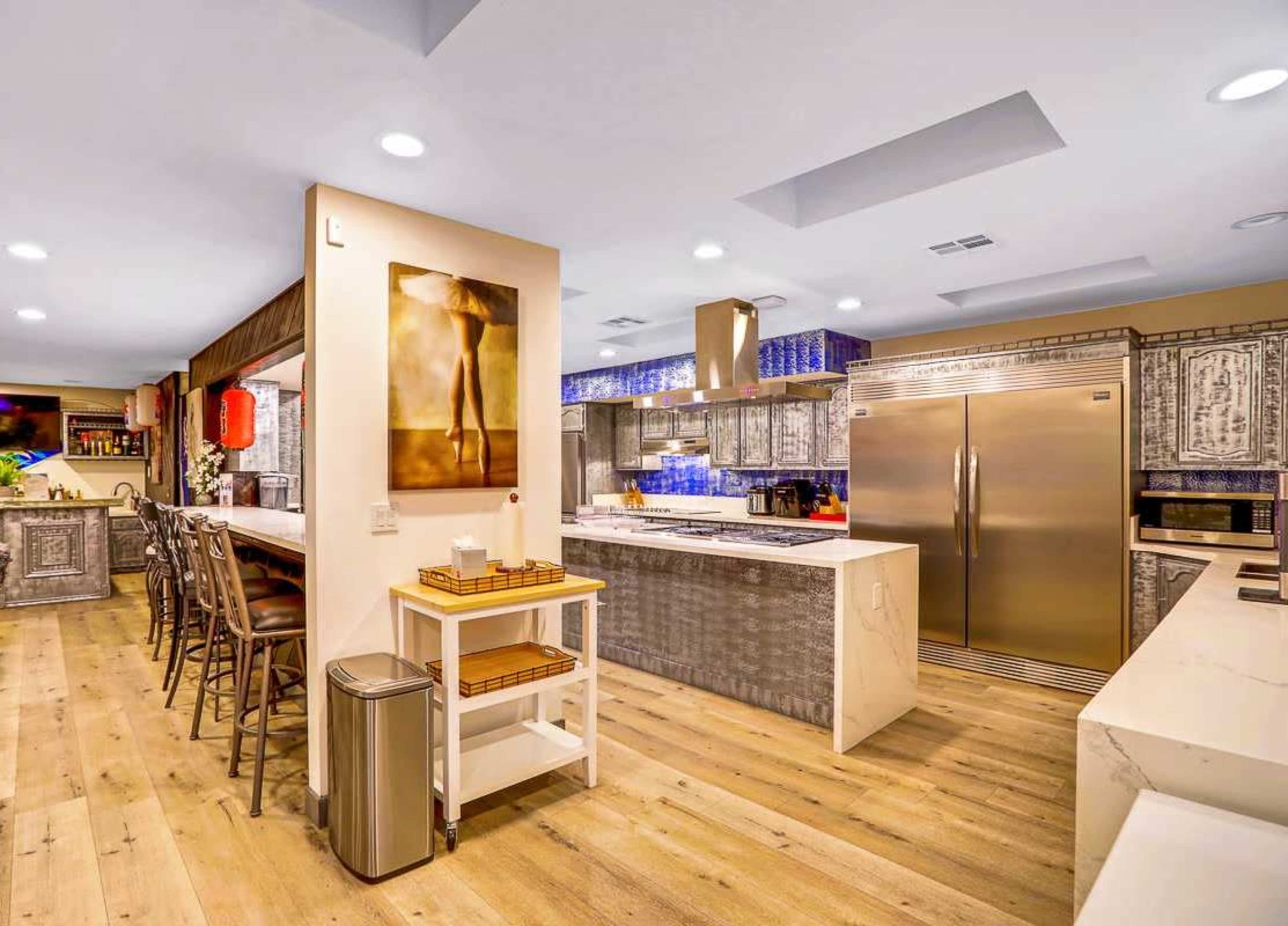 The kitchen features modern appliances, a central island, and wooden flooring with a decorative backsplash.