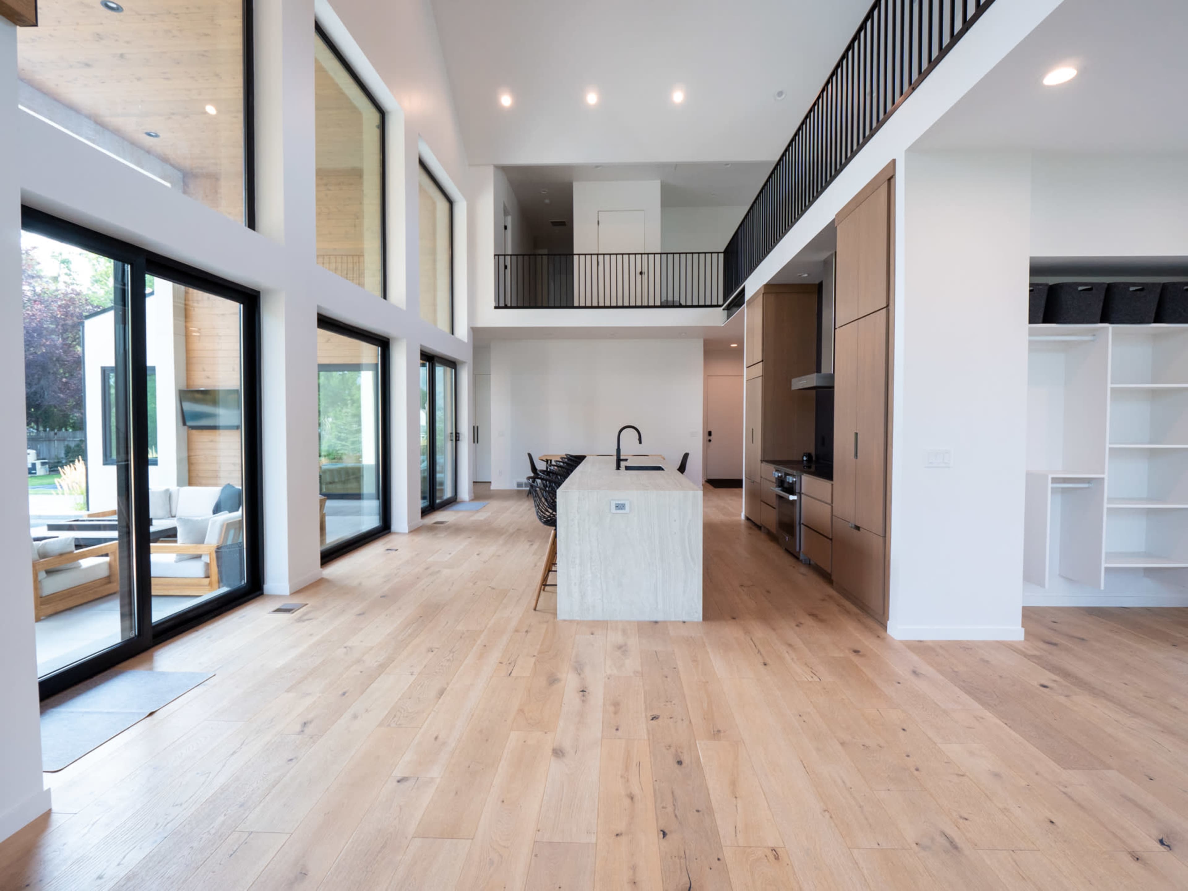 A modern interior space featuring a large kitchen island with bar stools, high ceilings, large windows, and an open floor plan.