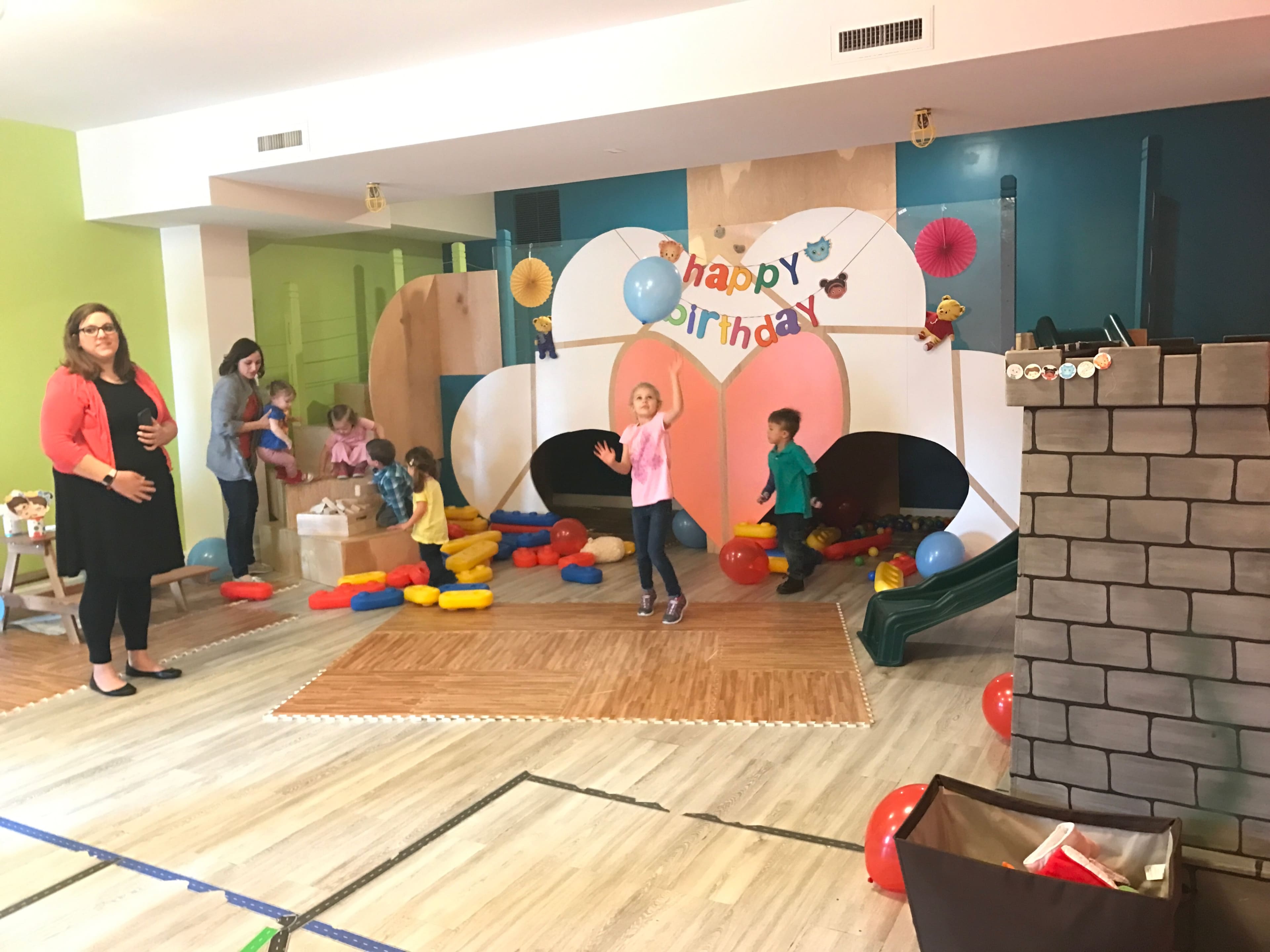 A colorful birthday party scene features children playing with balloons and toys, while adults supervise in a decorated indoor space.