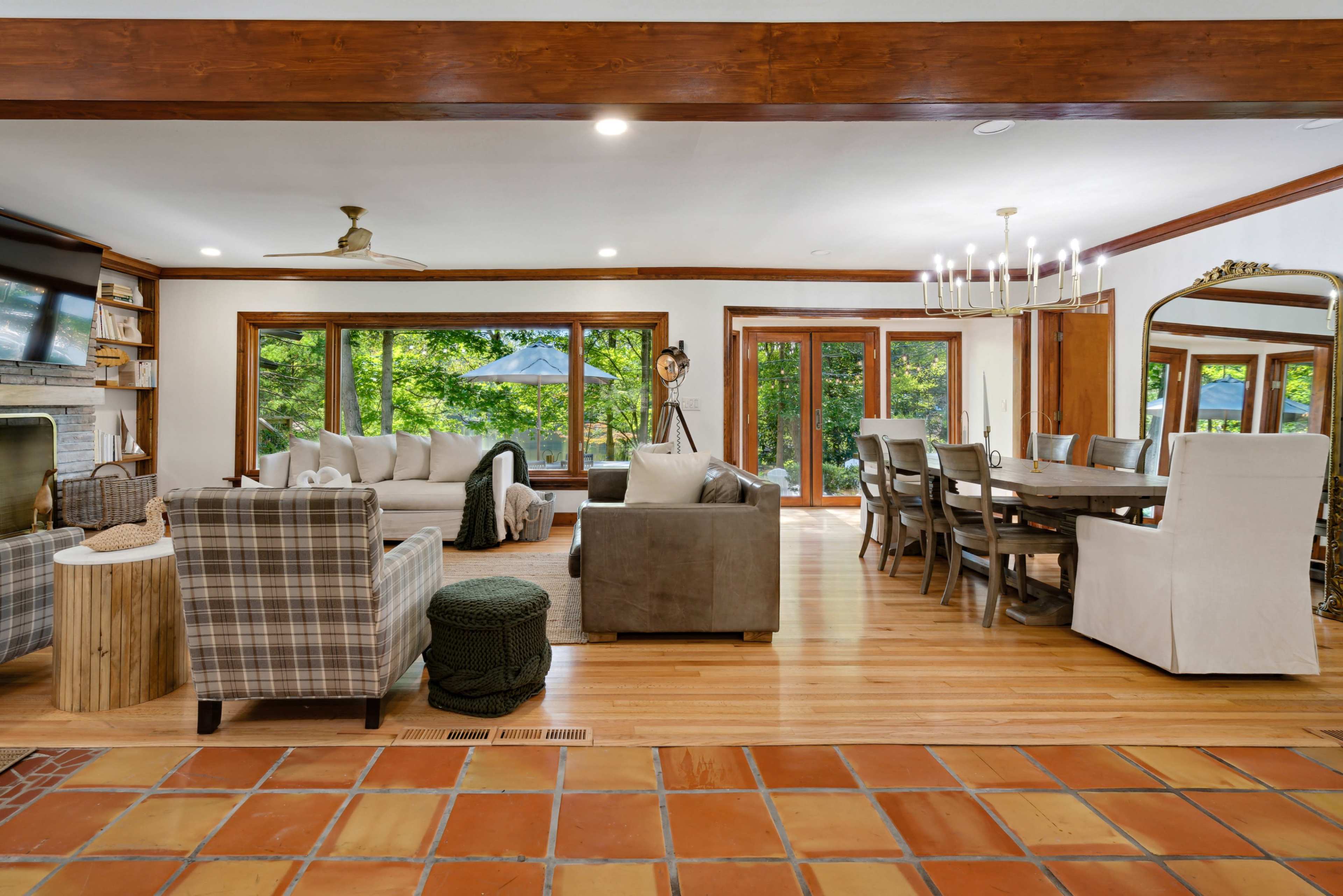 The interior of a spacious living area features a combination of seating arrangements, a dining table, and large windows that provide views of the outdoors.