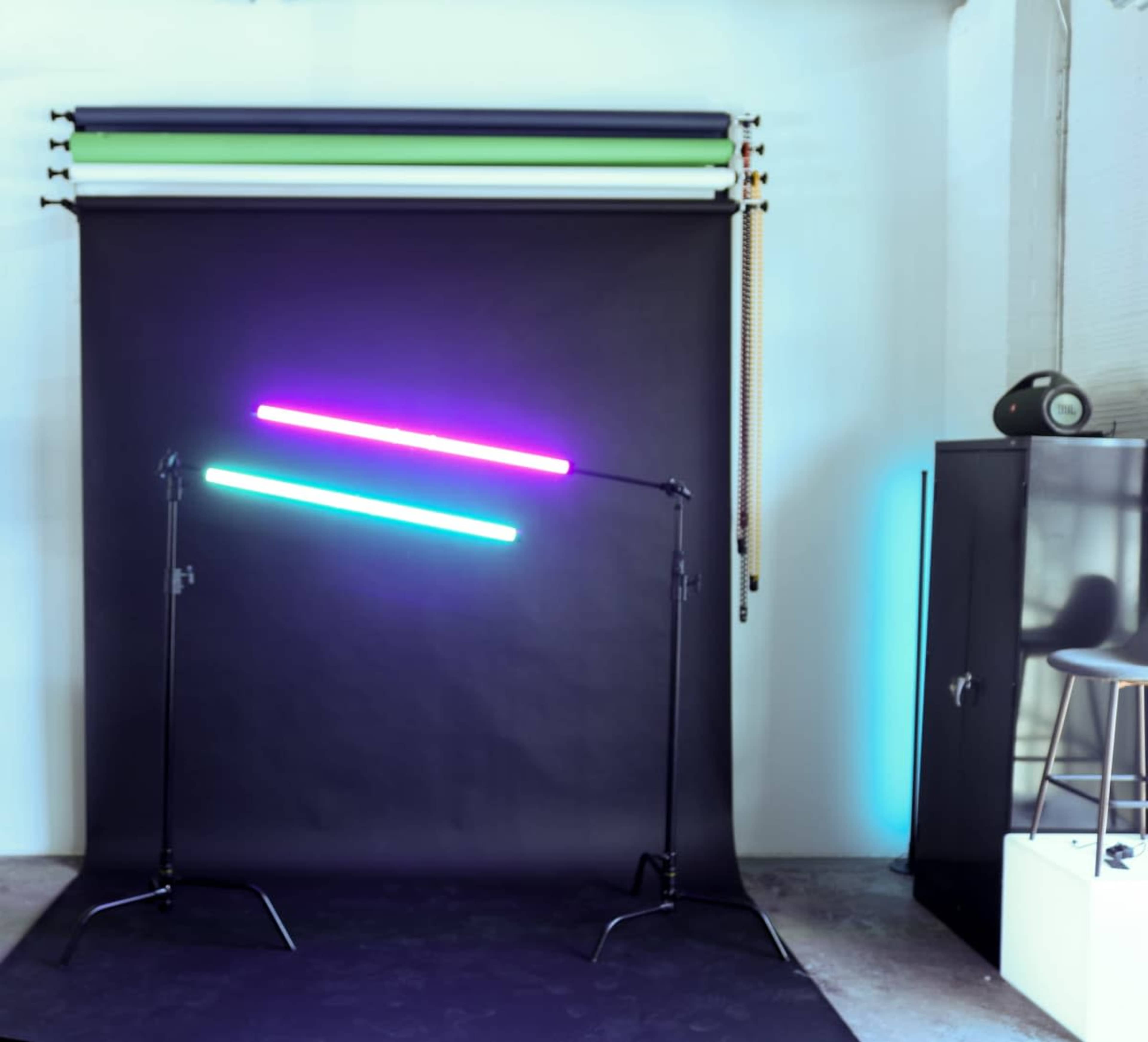 The image shows a photography studio setup with two illuminated light bars positioned at an angle against a dark backdrop.