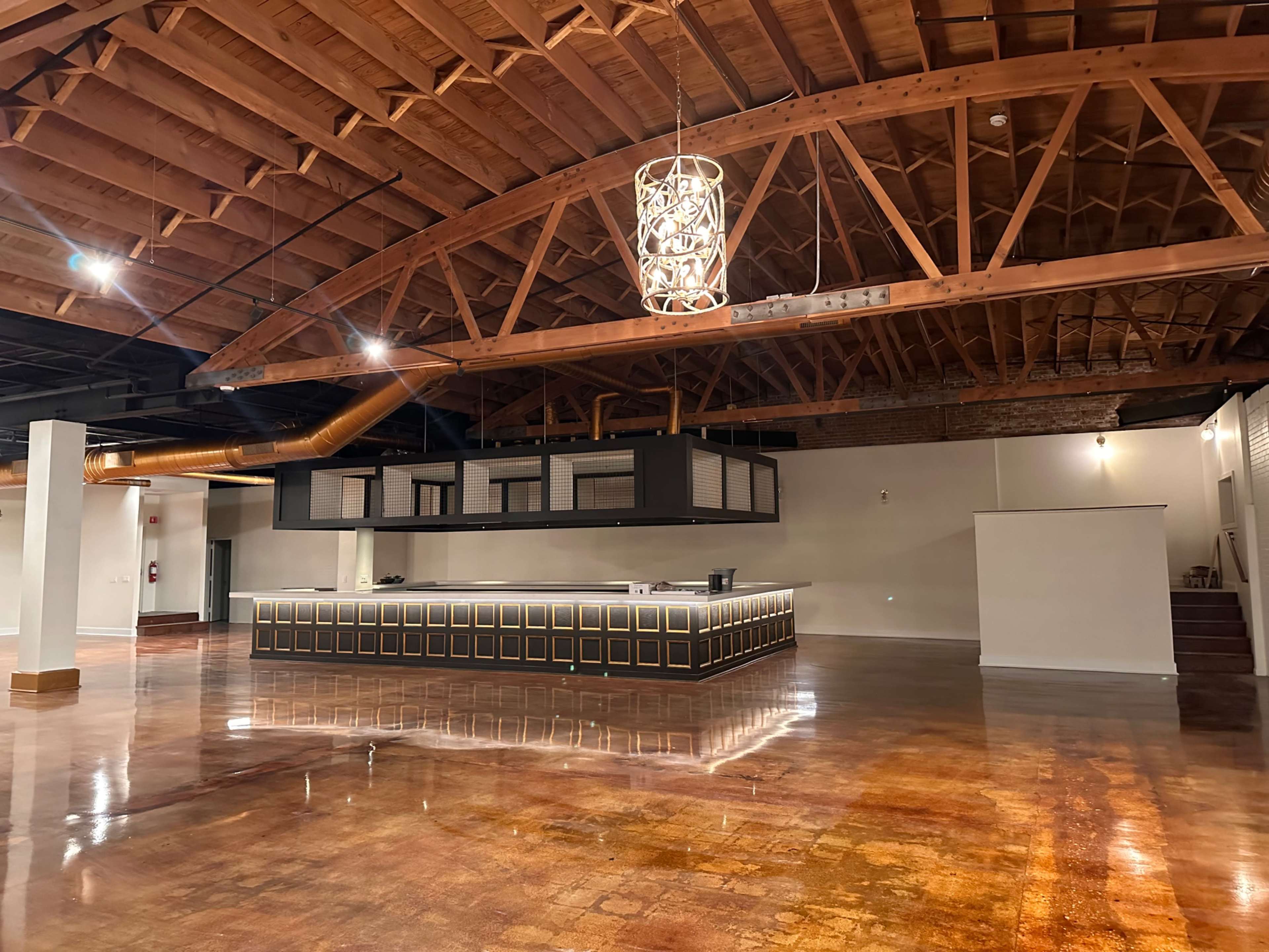 The image shows a spacious interior with polished concrete floors, wooden beams, and a modern reception desk.
