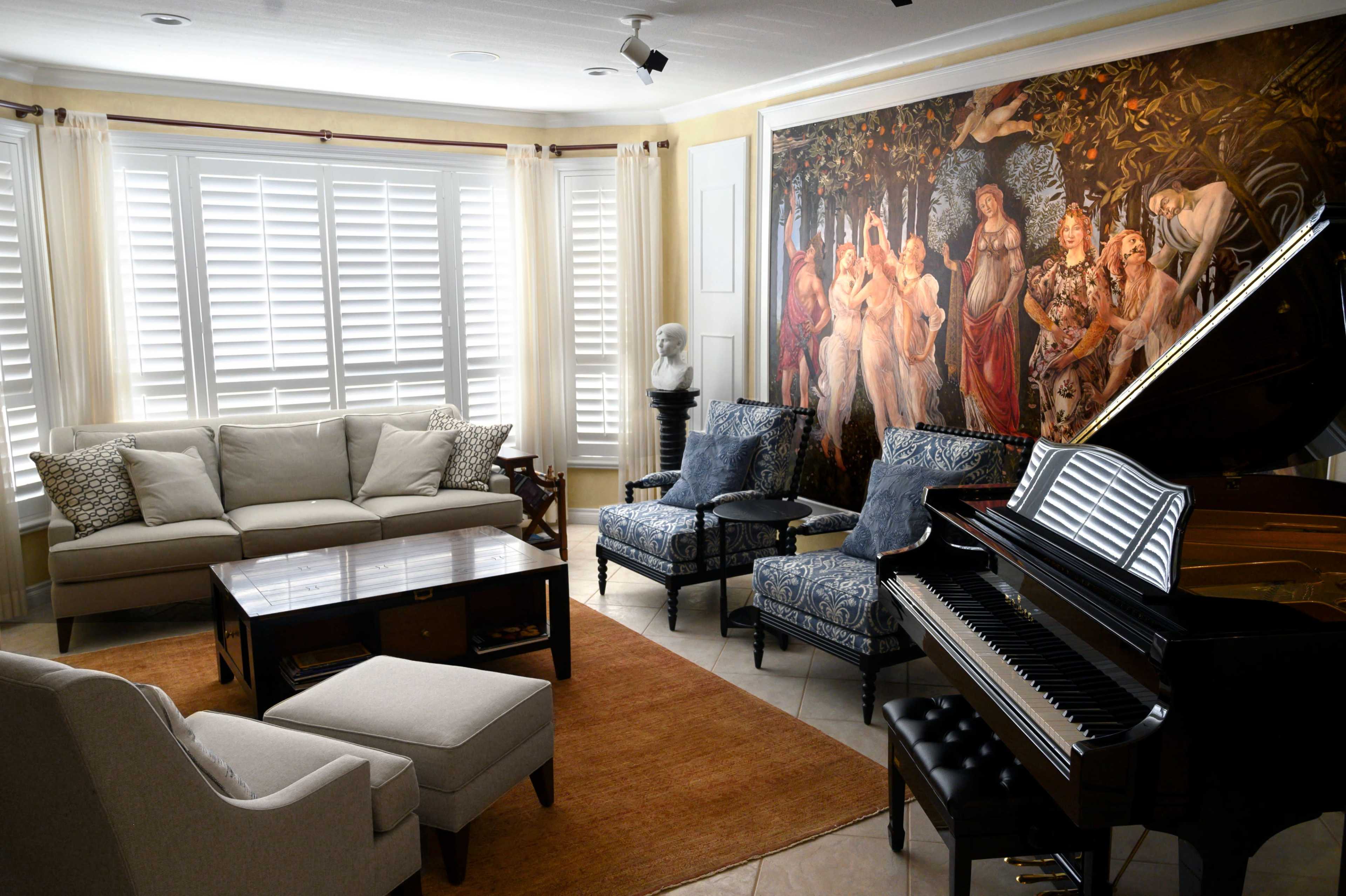 The living room features a grand piano, a large sectional sofa, upholstered chairs, a coffee table, and a decorative mural on the wall.
