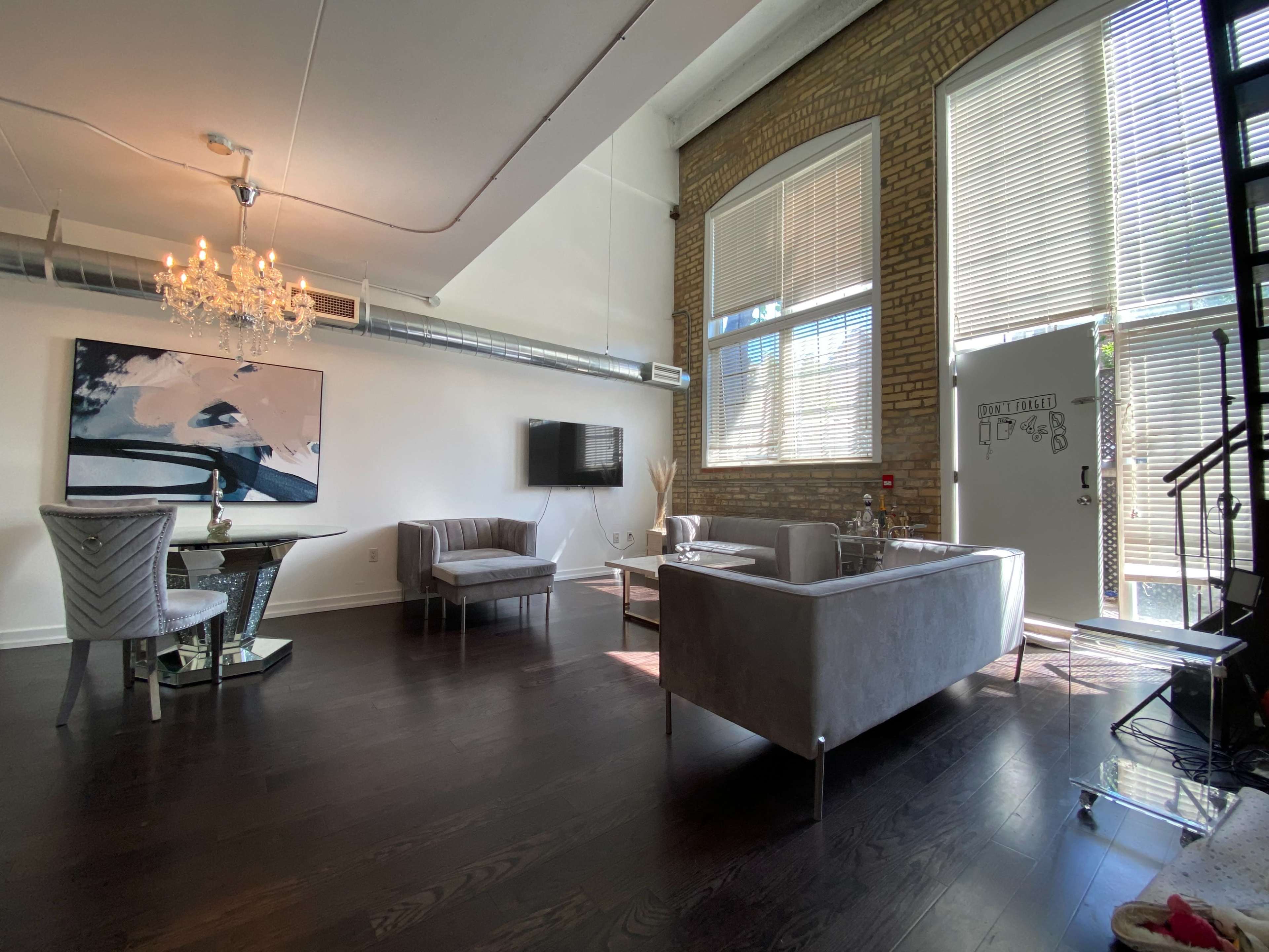 A modern living space with a seating area, a dining table, and large windows allowing natural light to enter.
