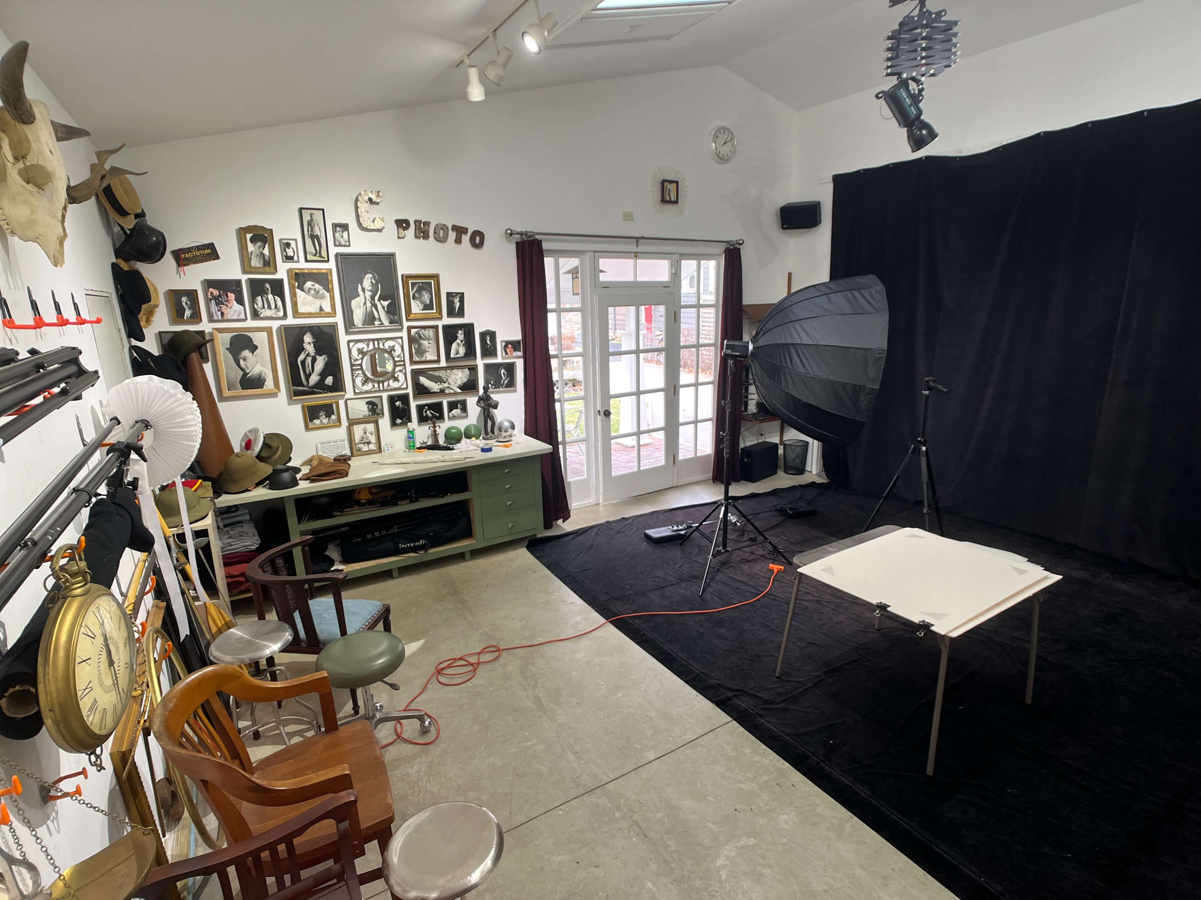 A photography studio features a backdrop, lighting equipment, and a collection of framed photographs on the wall.