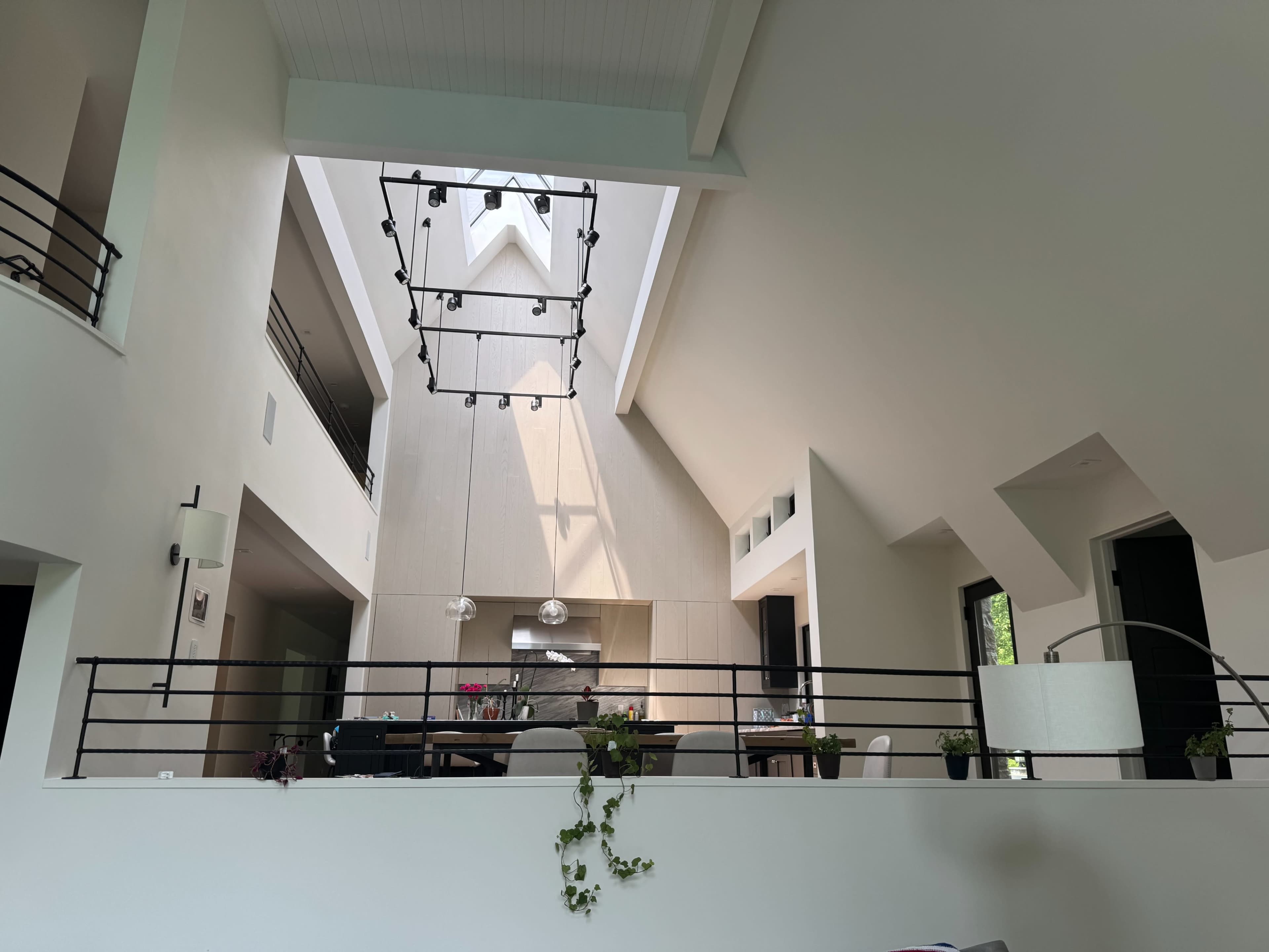 A spacious, modern interior features high ceilings, large windows, and a central dining area illuminated by natural light.