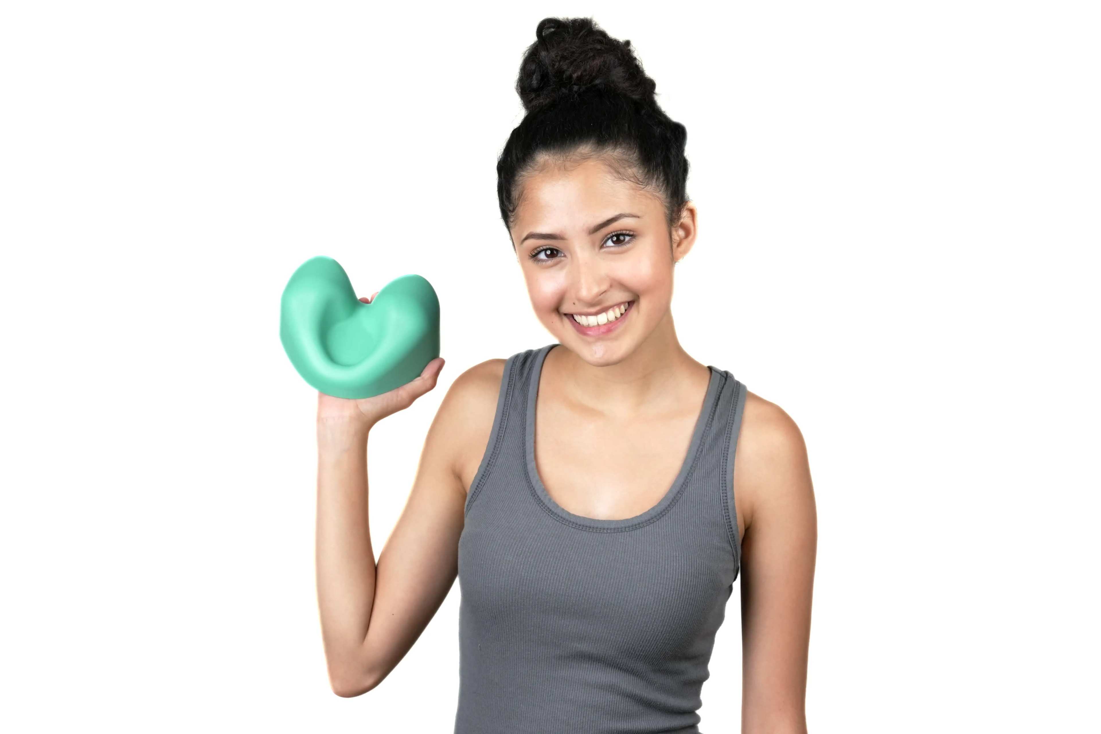 A young woman in a gray tank top holds a green, heart-shaped object while smiling.