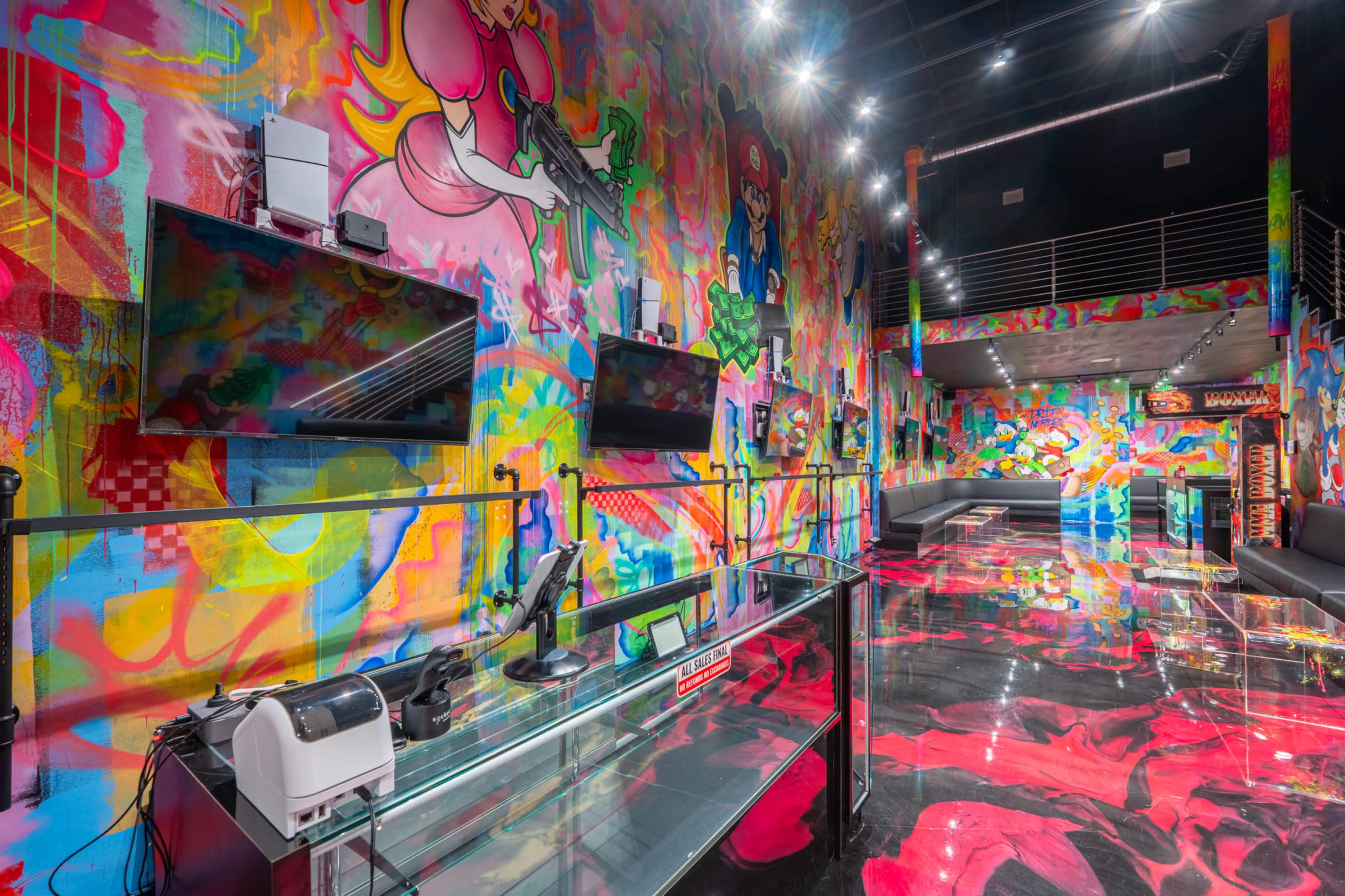The image shows a vibrant arcade with colorful graffiti-covered walls and shiny, reflective flooring, featuring multiple screens mounted on the walls.