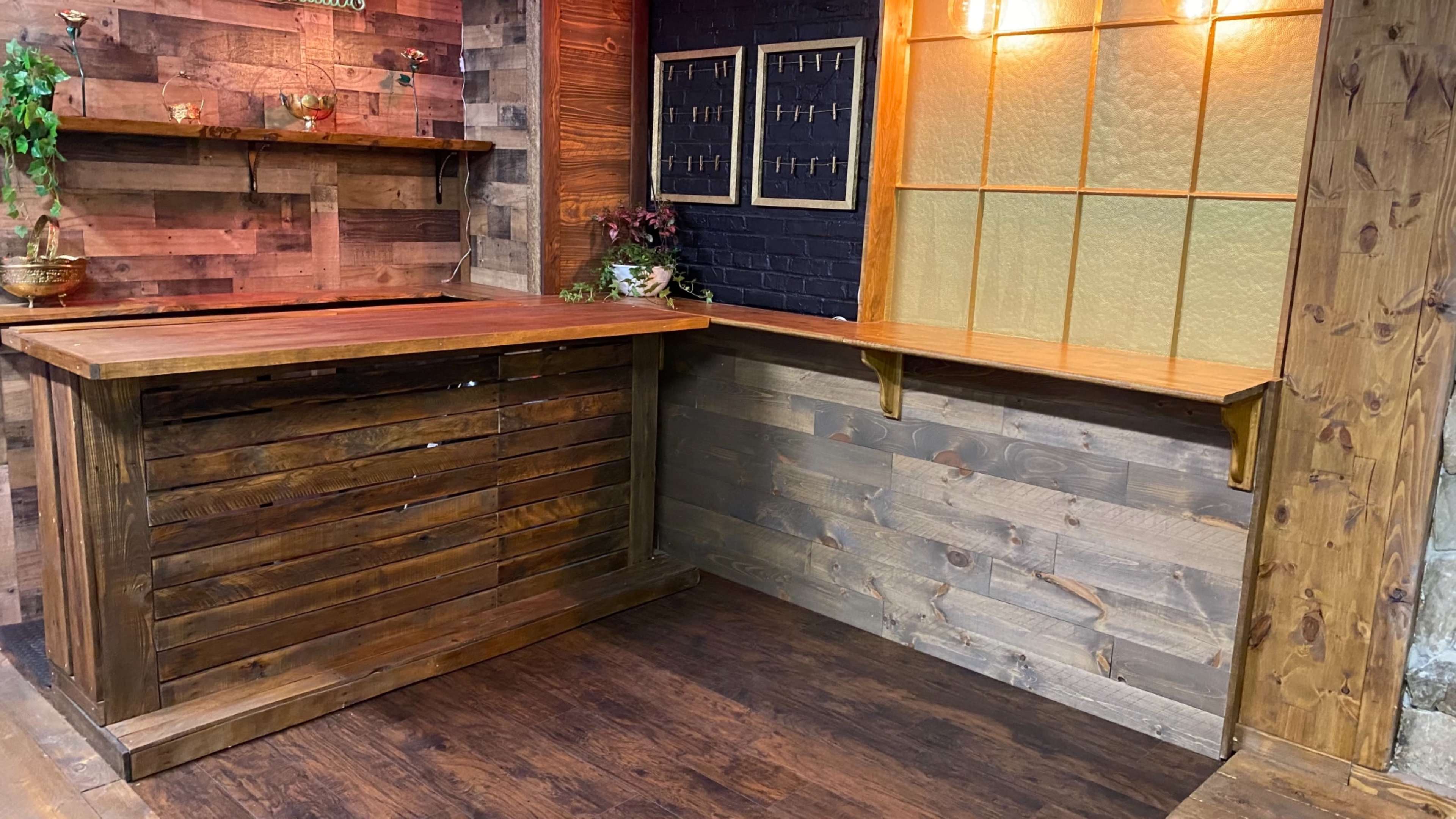 A wooden bar area with slatted design and a window featuring frosted glass, set against a backdrop of rustic wooden walls.