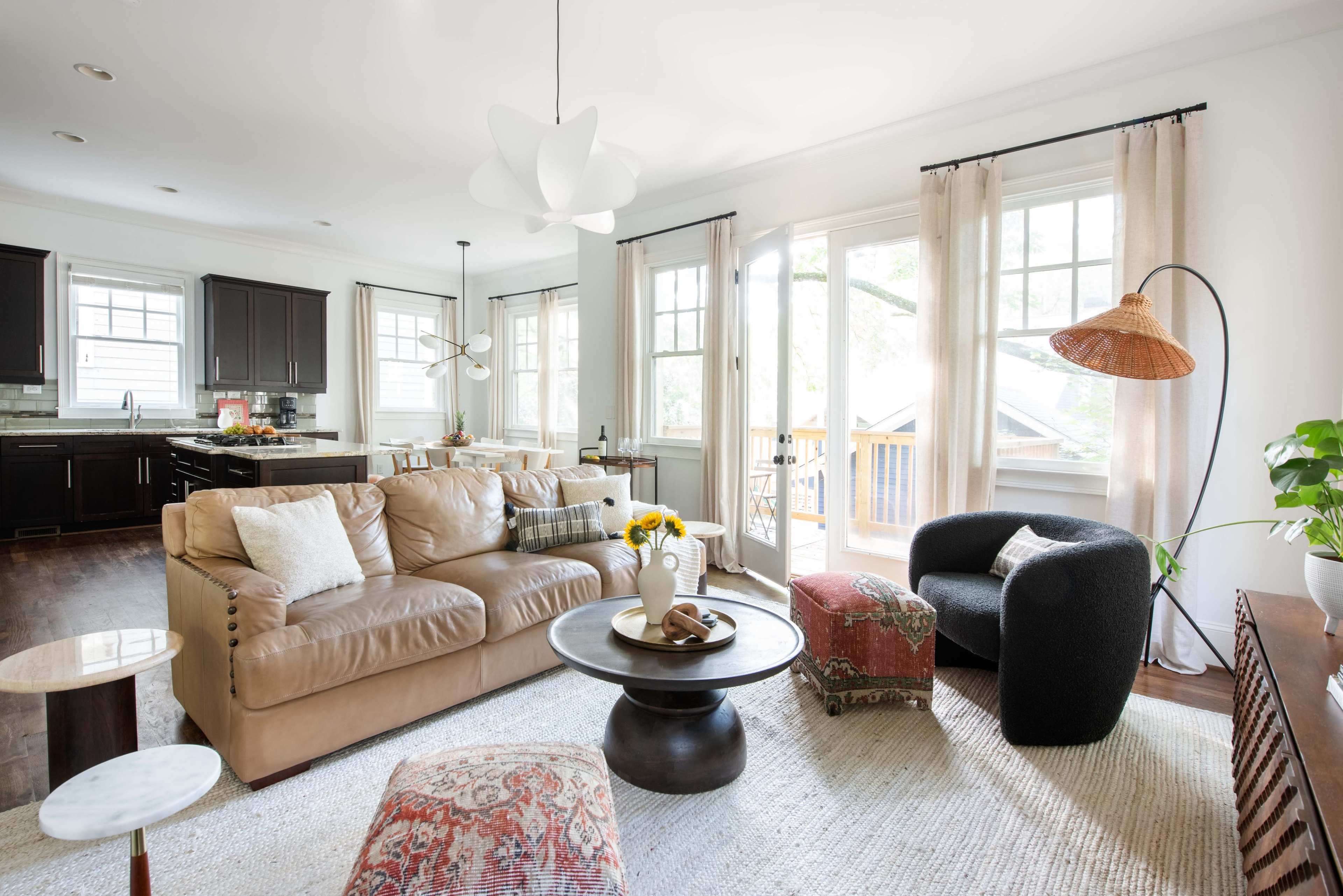 A modern living room with a leather sofa, a round coffee table, and large windows that allow natural light to fill the space.