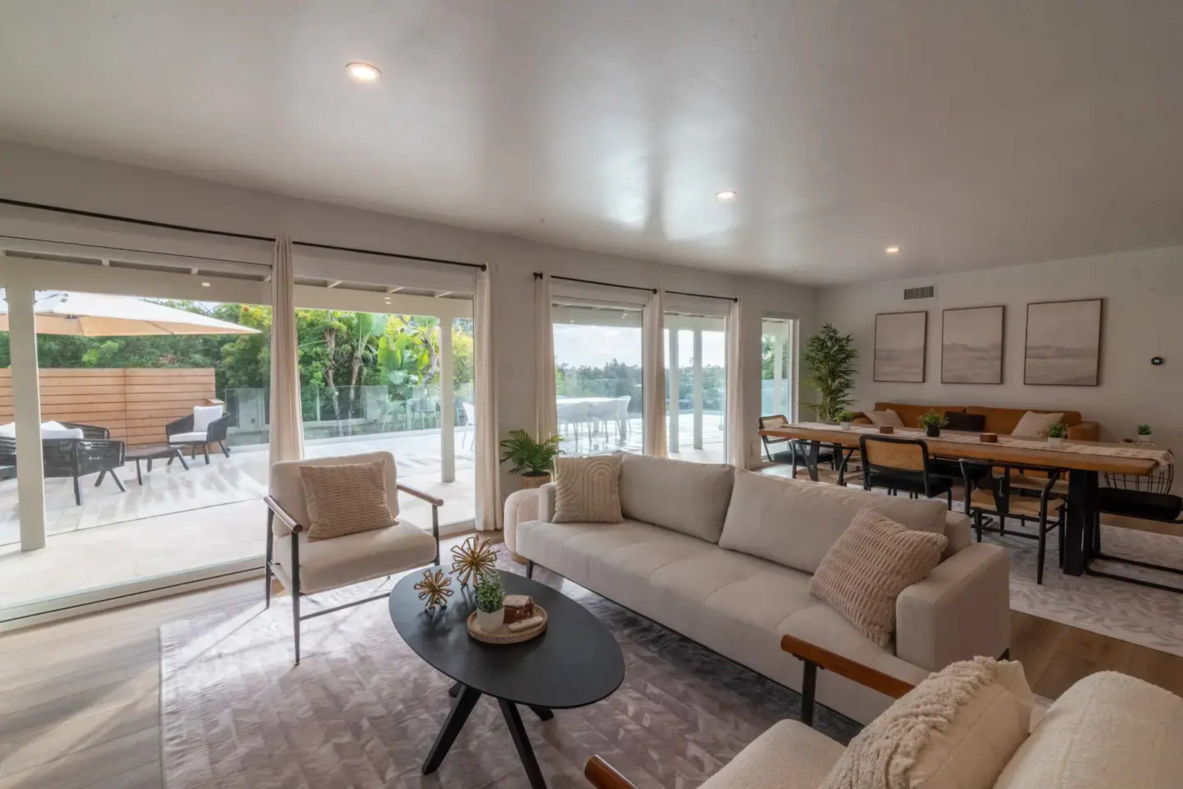 A modern living room with a light-colored sofa, a round coffee table, and large windows that provide a view of an outdoor area.
