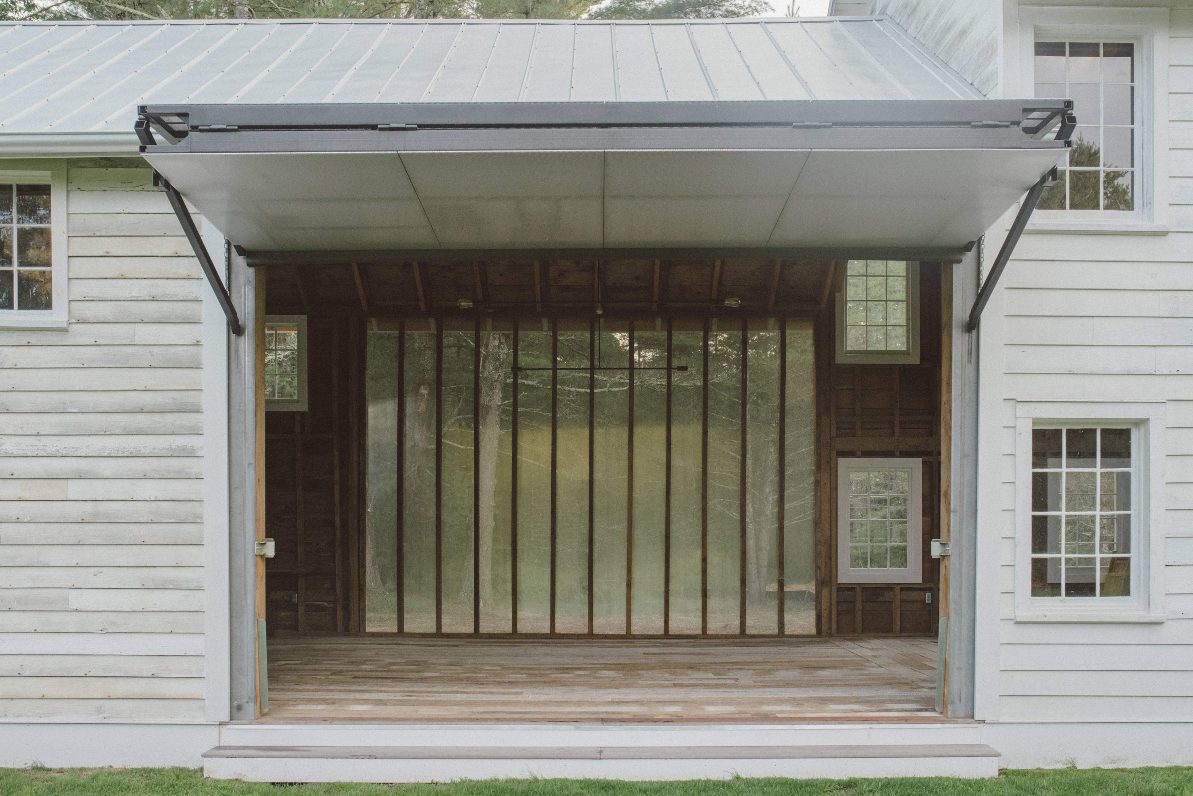 An open section of a house with large sliding doors leading to a wooden deck and a grassy area outside.