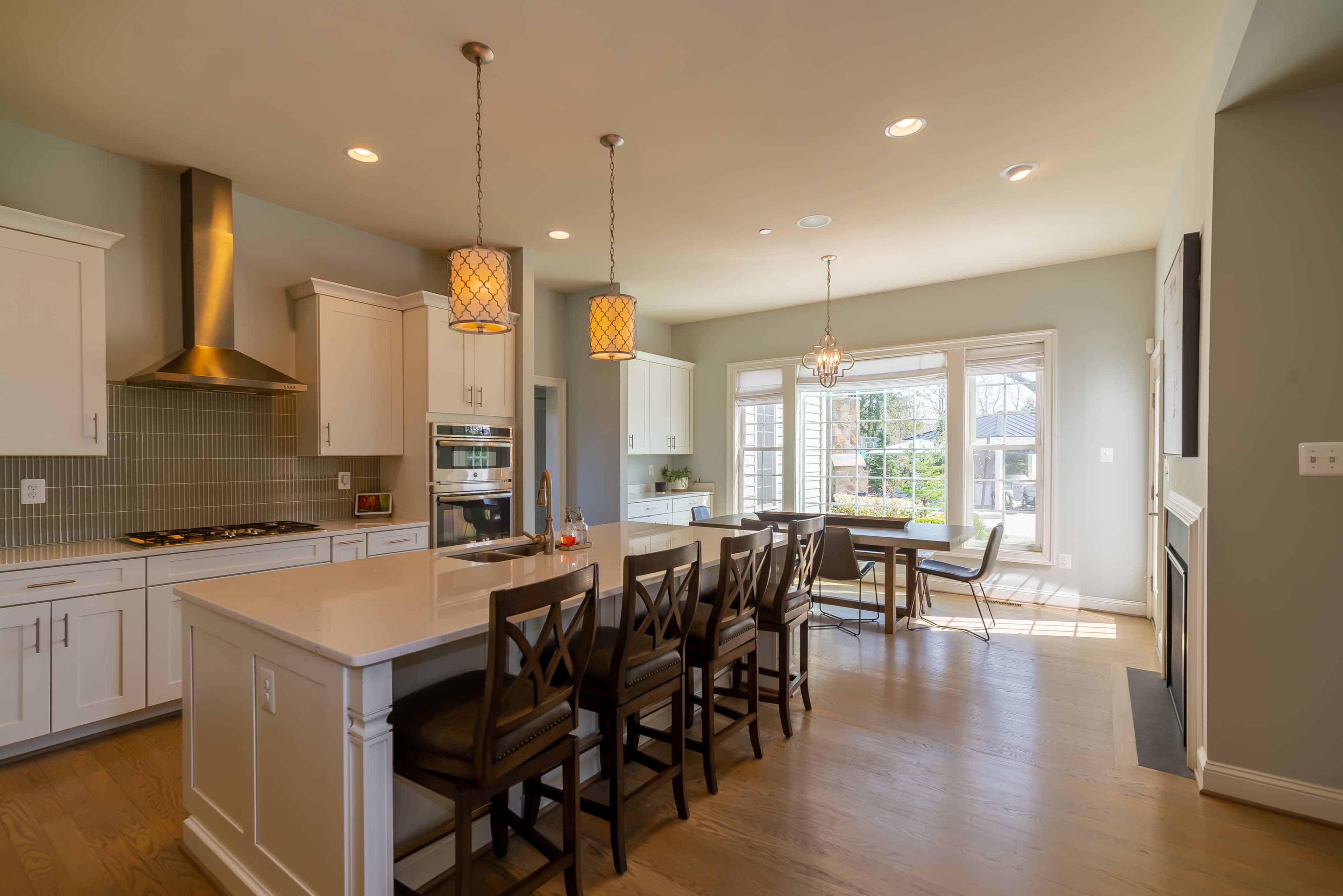 A modern kitchen features white cabinetry, stainless steel appliances, and an island with seating.