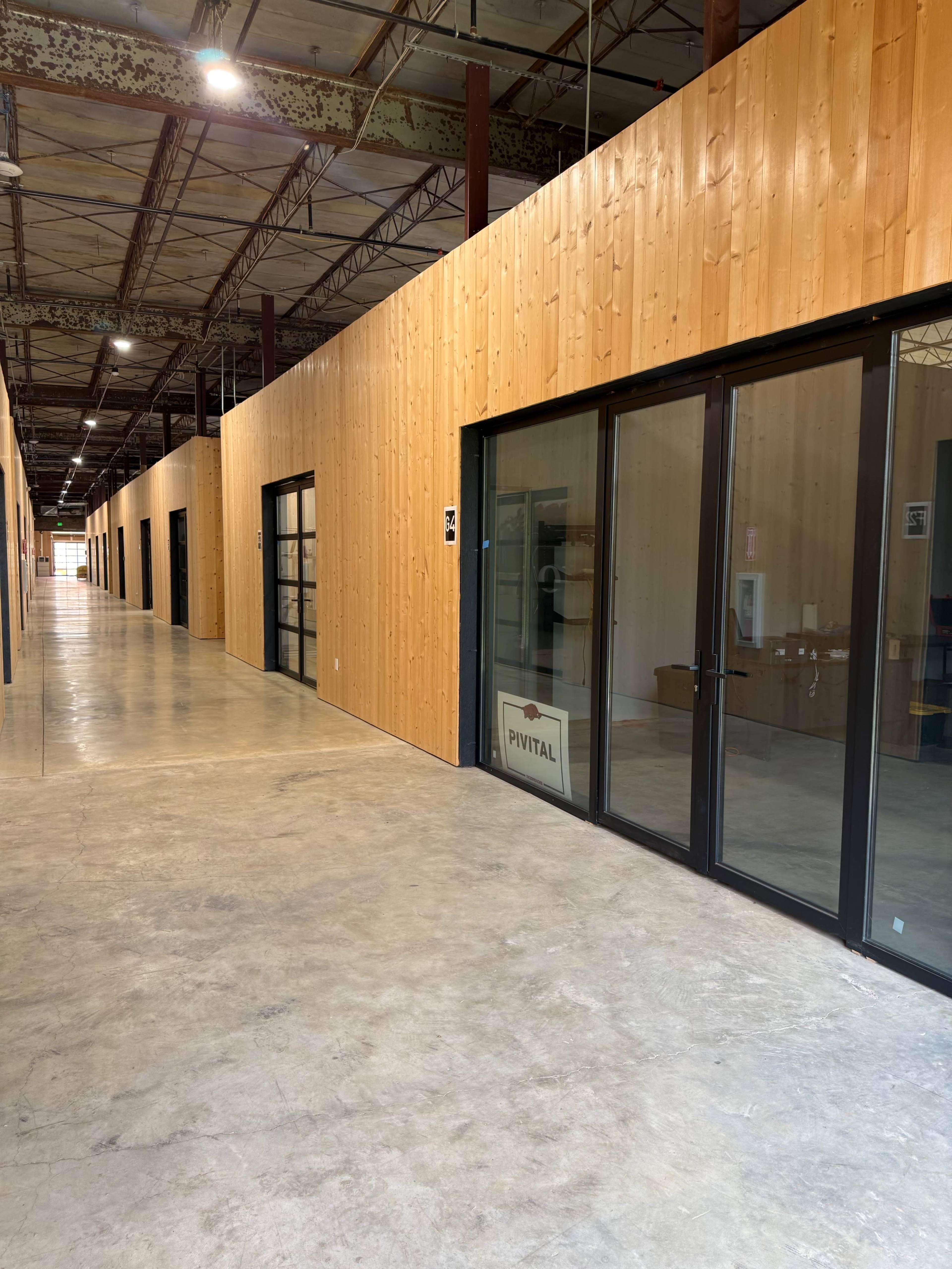 The image shows a long hallway with wooden-paneled walls and glass-paneled office doors on either side.