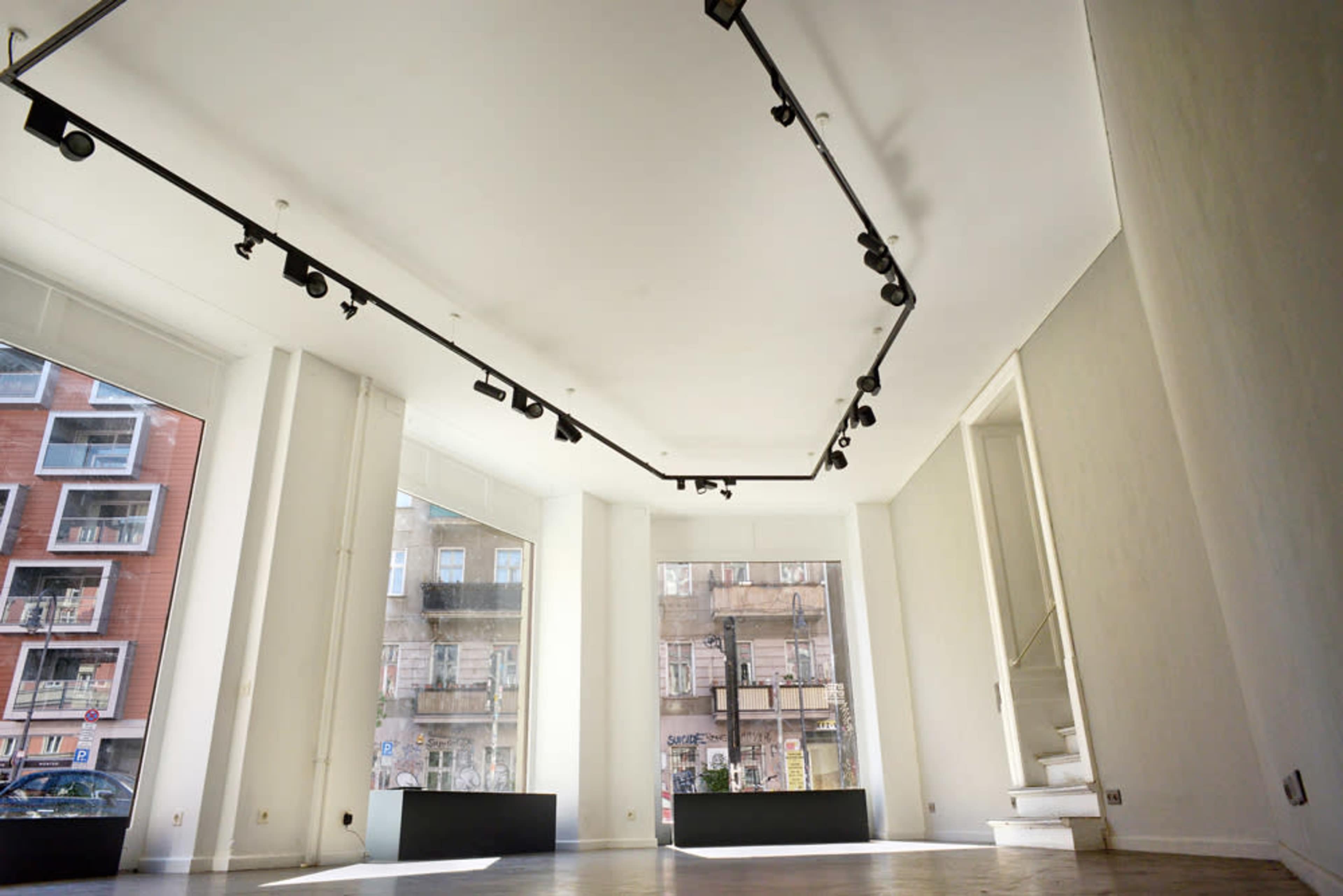 A spacious, empty retail space with large windows and a unique lighting track along the ceiling.