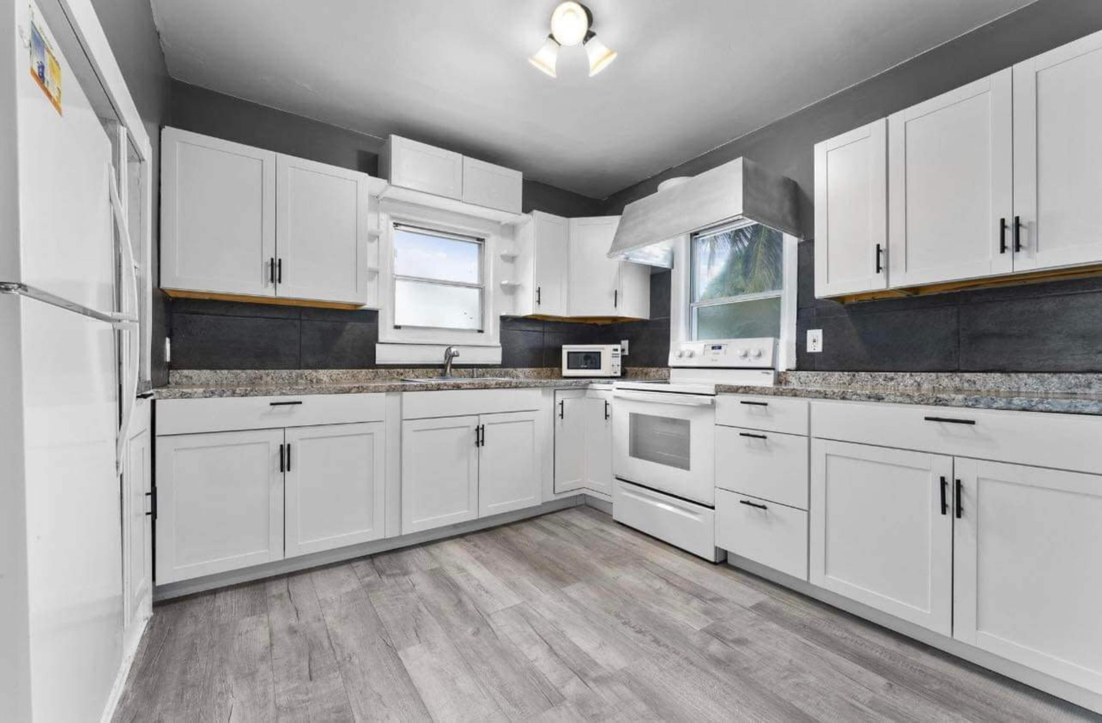 The kitchen features white cabinets, granite countertops, and modern appliances, with a window providing natural light.