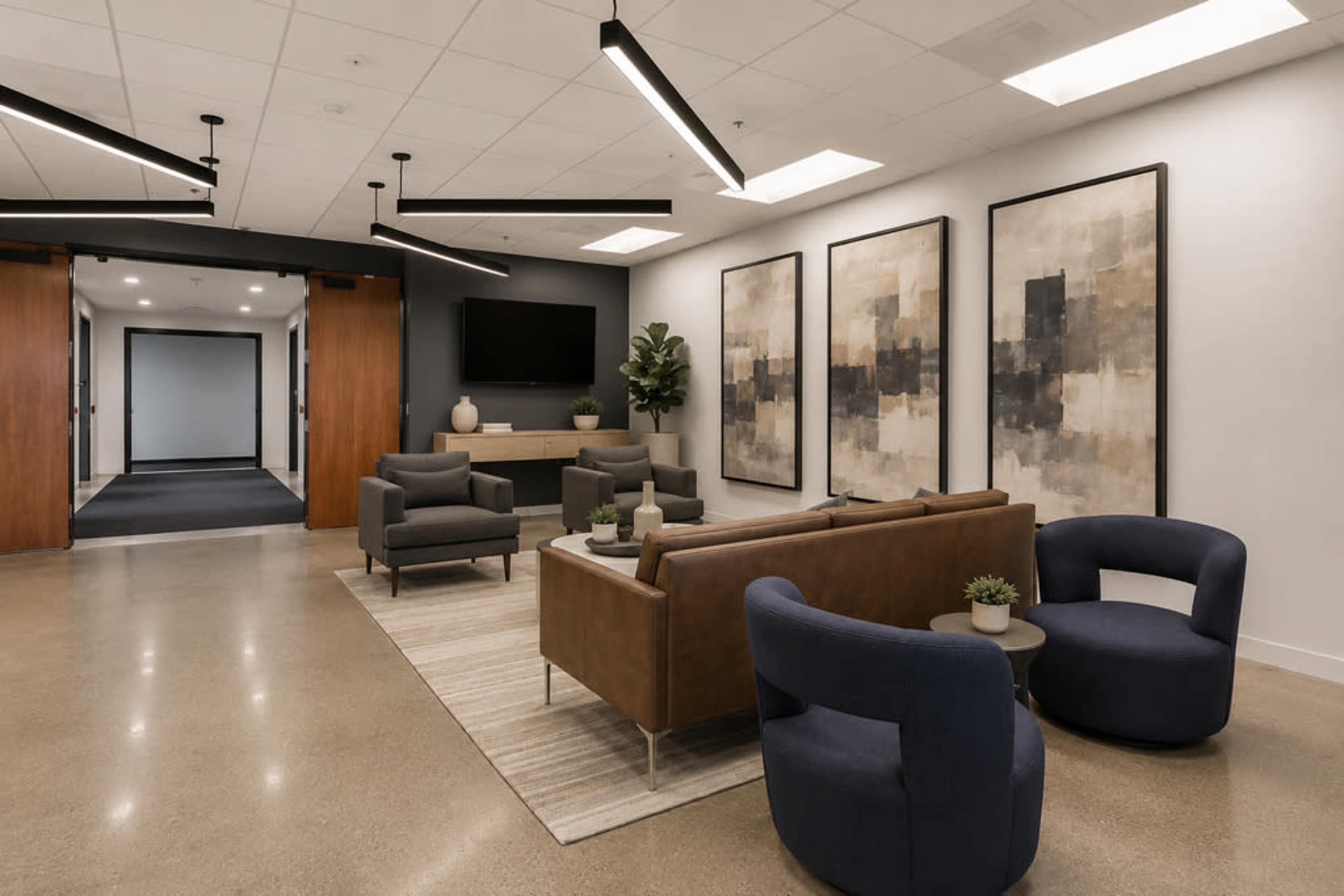 The image shows a modern lobby area with two sofas, seating chairs, a coffee table, and abstract artwork on the walls.