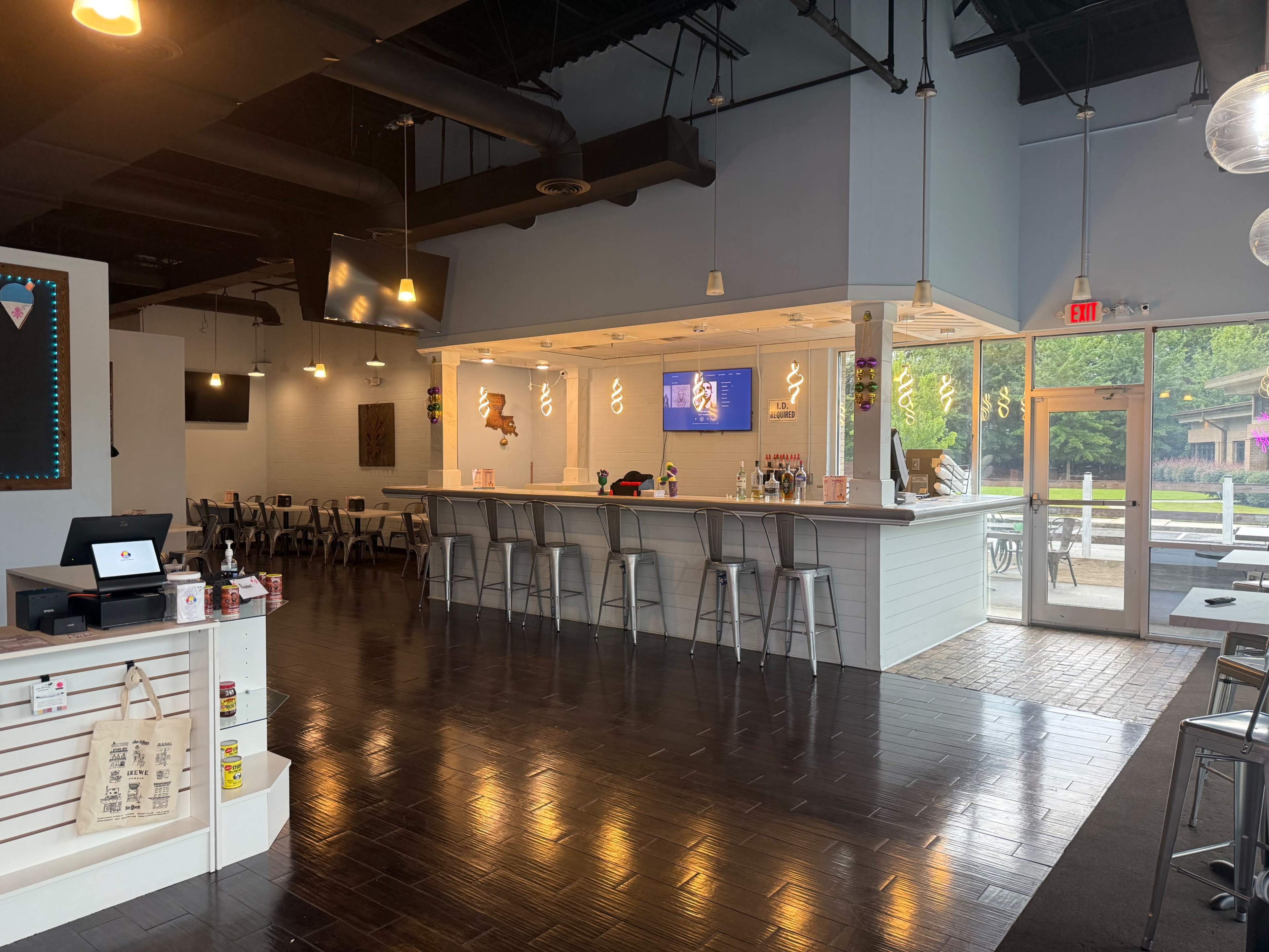 The interior of a modern café features a bar area with seating, large windows that let in natural light, and a minimalist design.