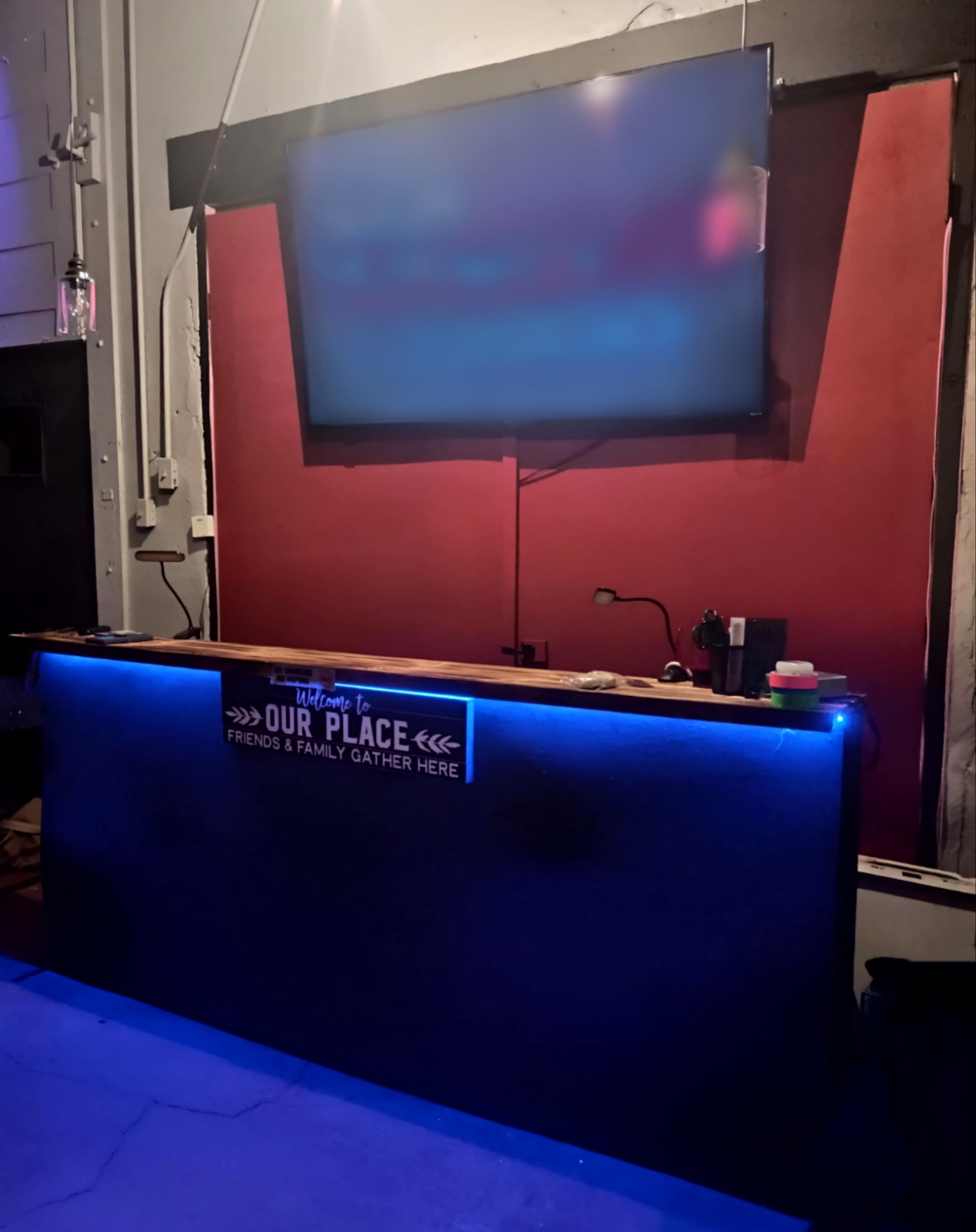 A bar area features a illuminated counter with a large television mounted on the wall behind it.
