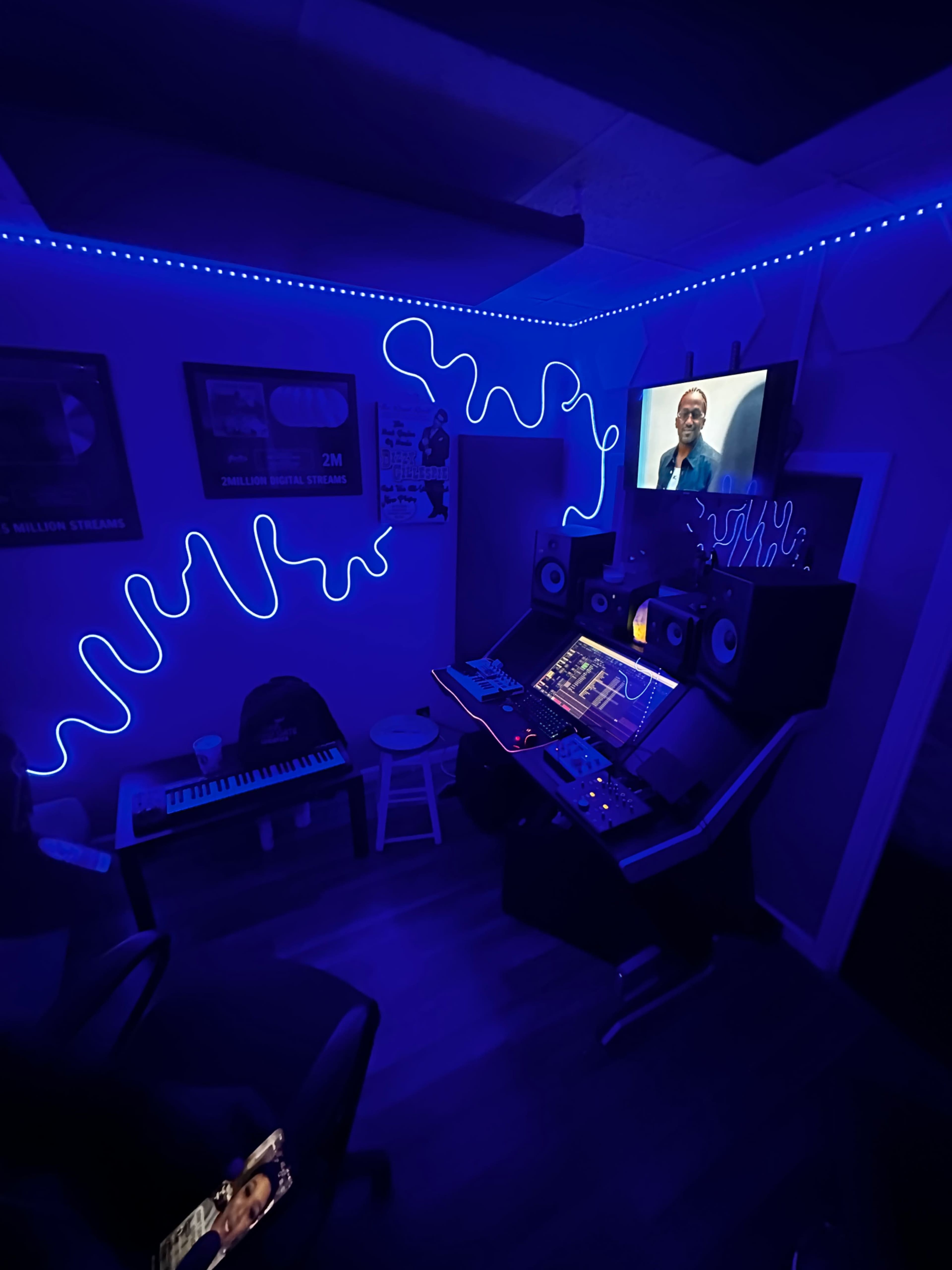 A music studio features a digital audio workstation, a keyboard, and blue LED lighting.