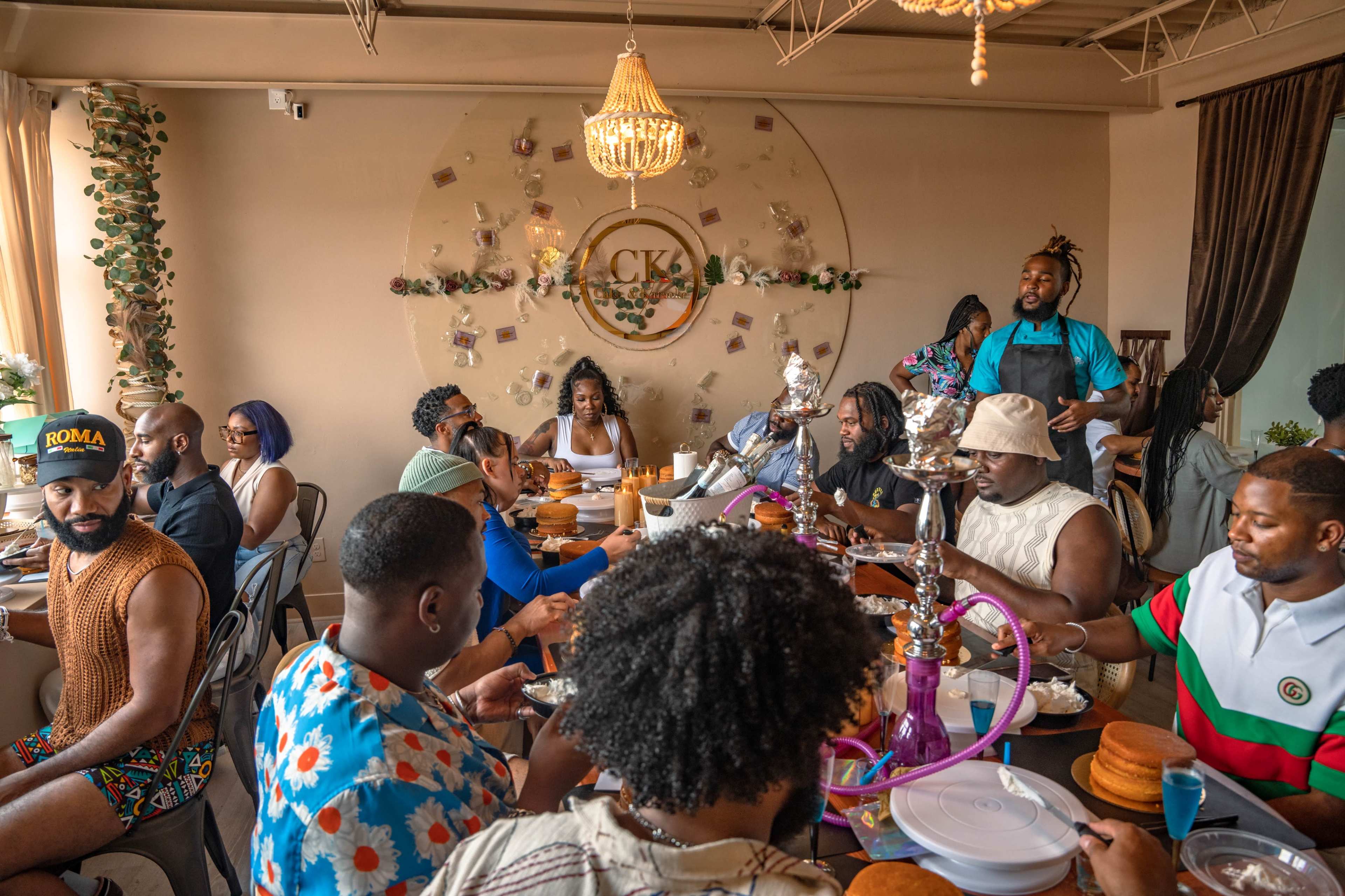 A group of people is gathered around a large table in a stylish restaurant, enjoying food and conversation.