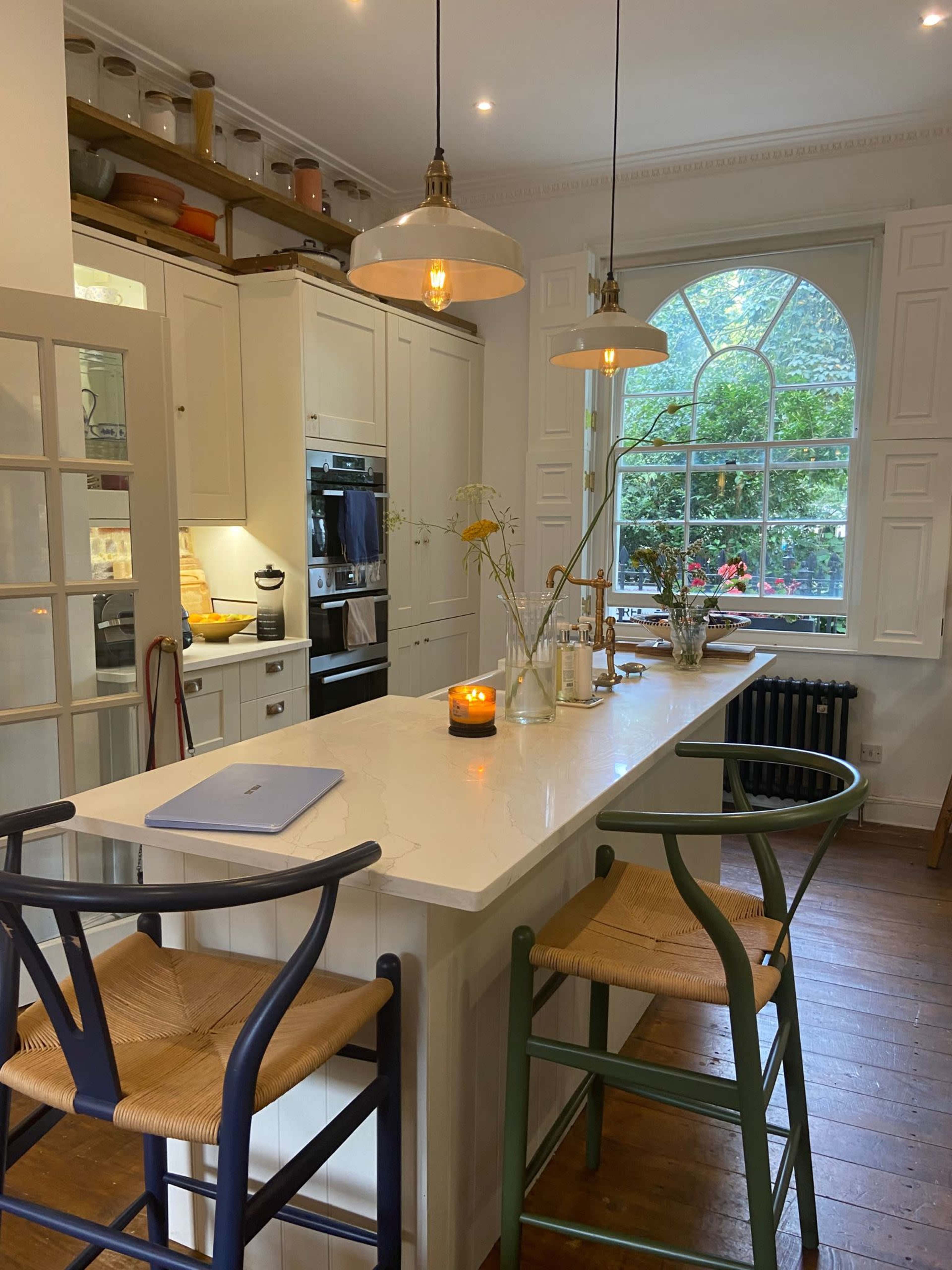 A modern kitchen with a central island, two pendant lights, and large windows allowing natural light to illuminate the space.