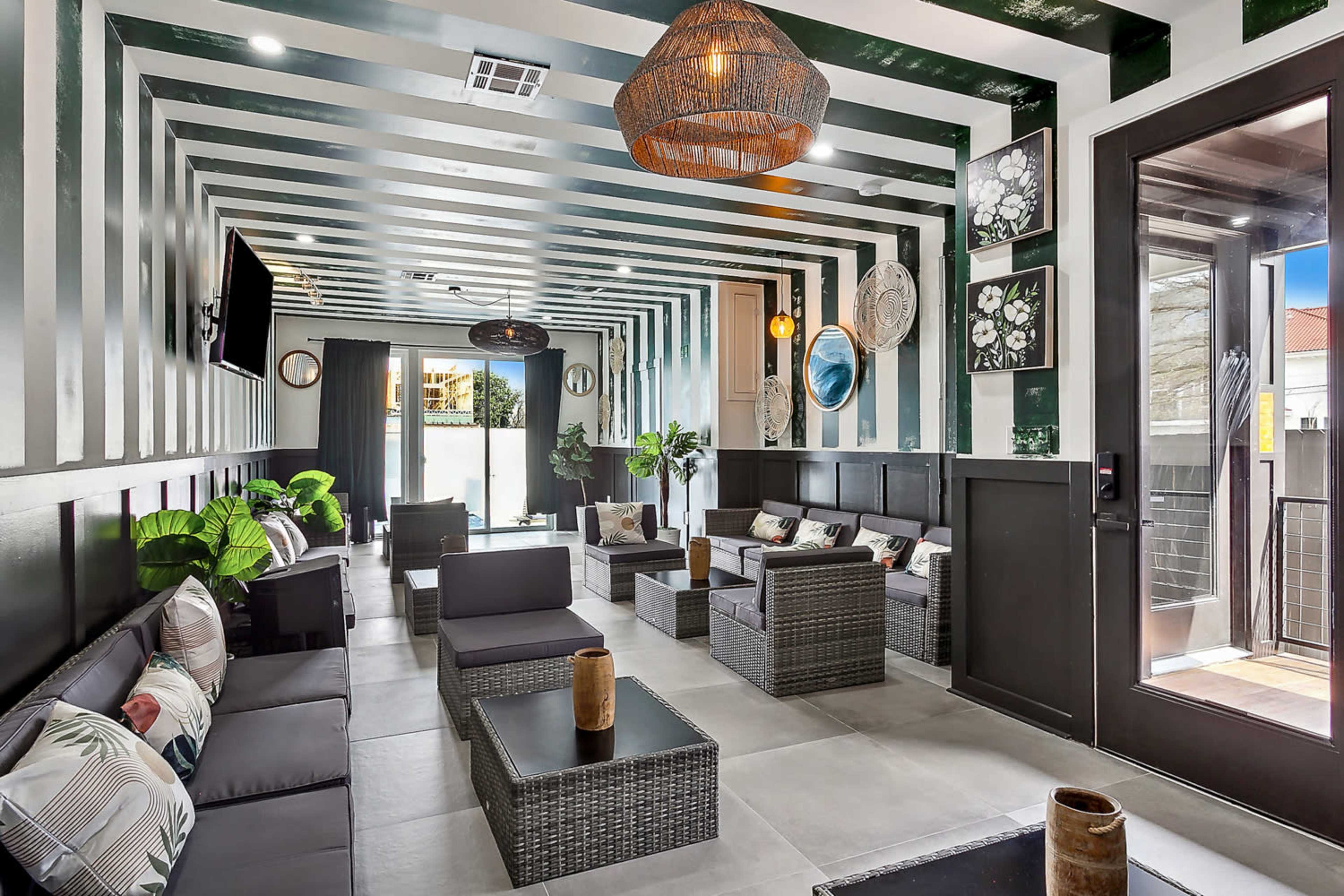 A modern lounge area features striped walls, stylish seating, and decorative plants.
