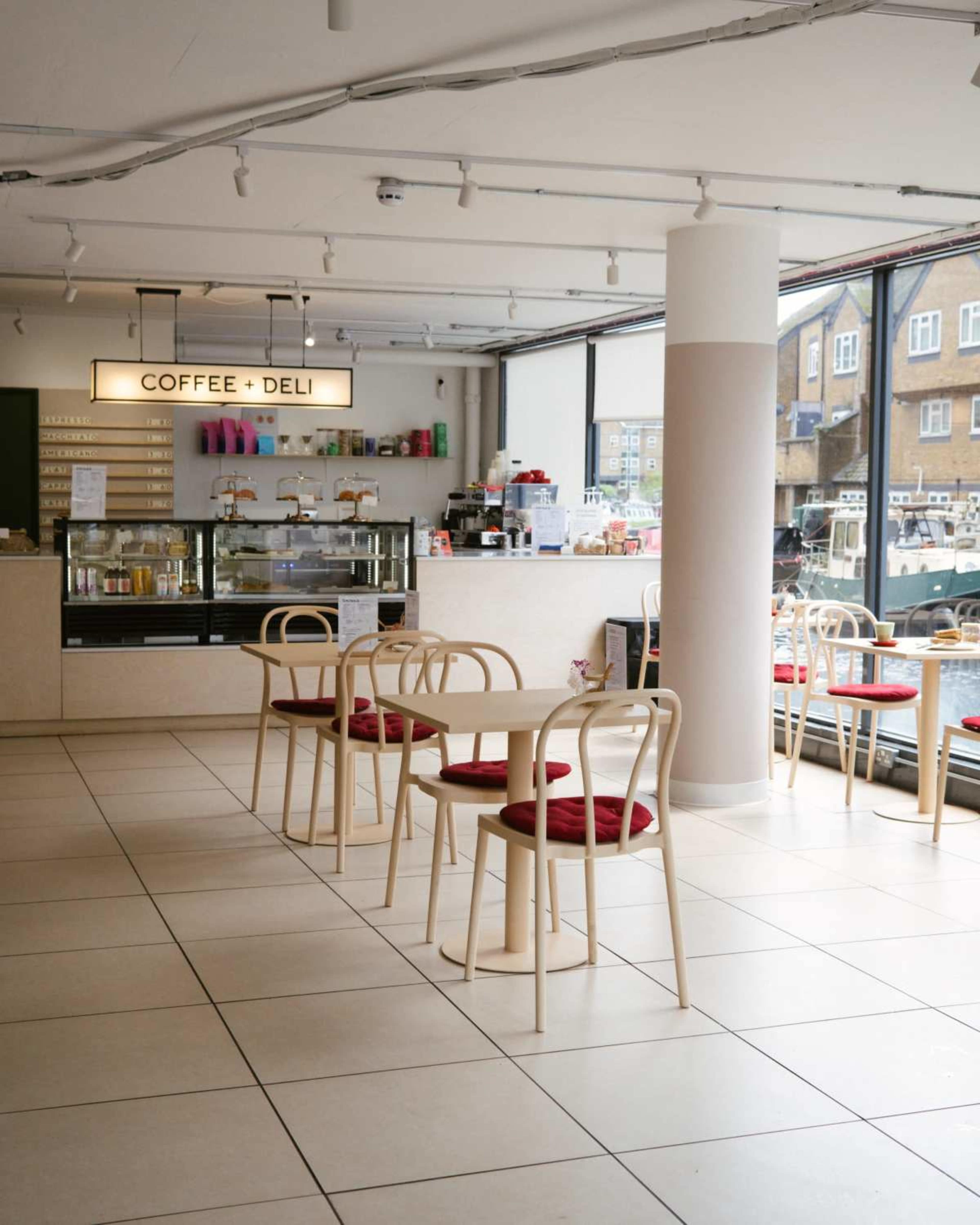 A modern coffee shop features a counter with various colorful items and minimalistic tables arranged in the seating area.