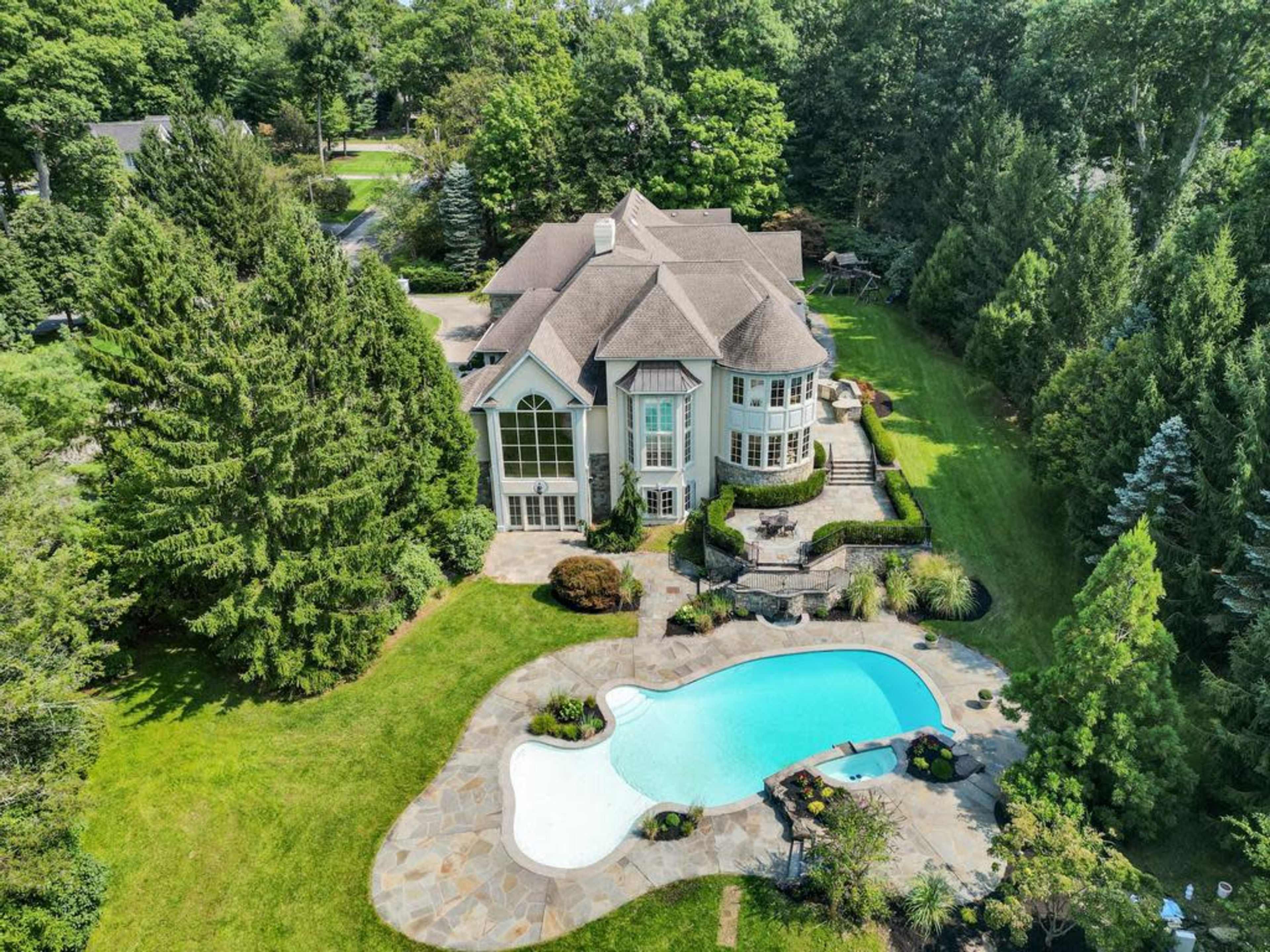 The image shows a large estate with a swimming pool surrounded by landscaped gardens.