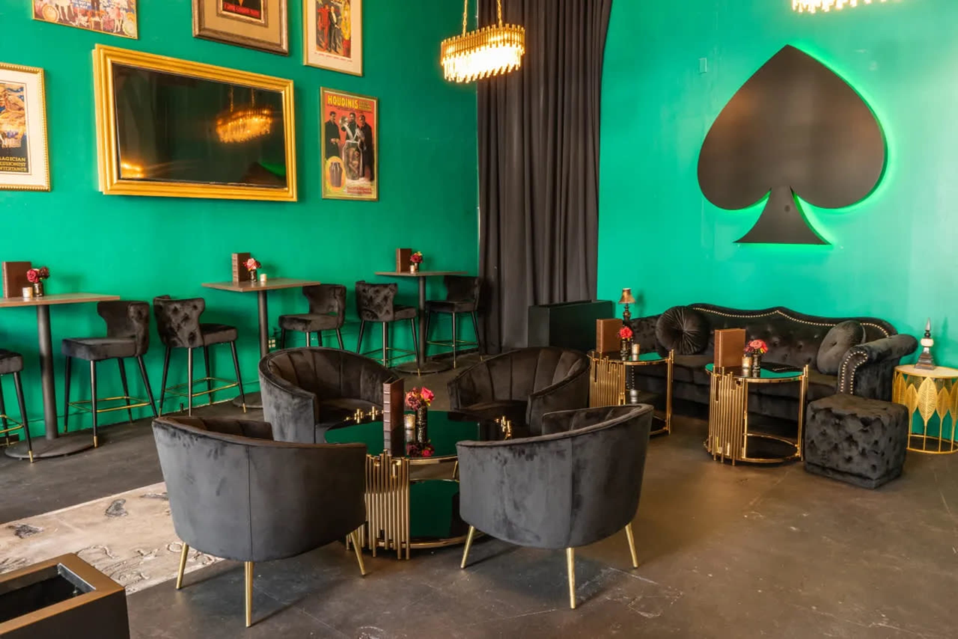 A vibrant green lounge area featuring plush black seating, stylish tables, and framed art on the walls.