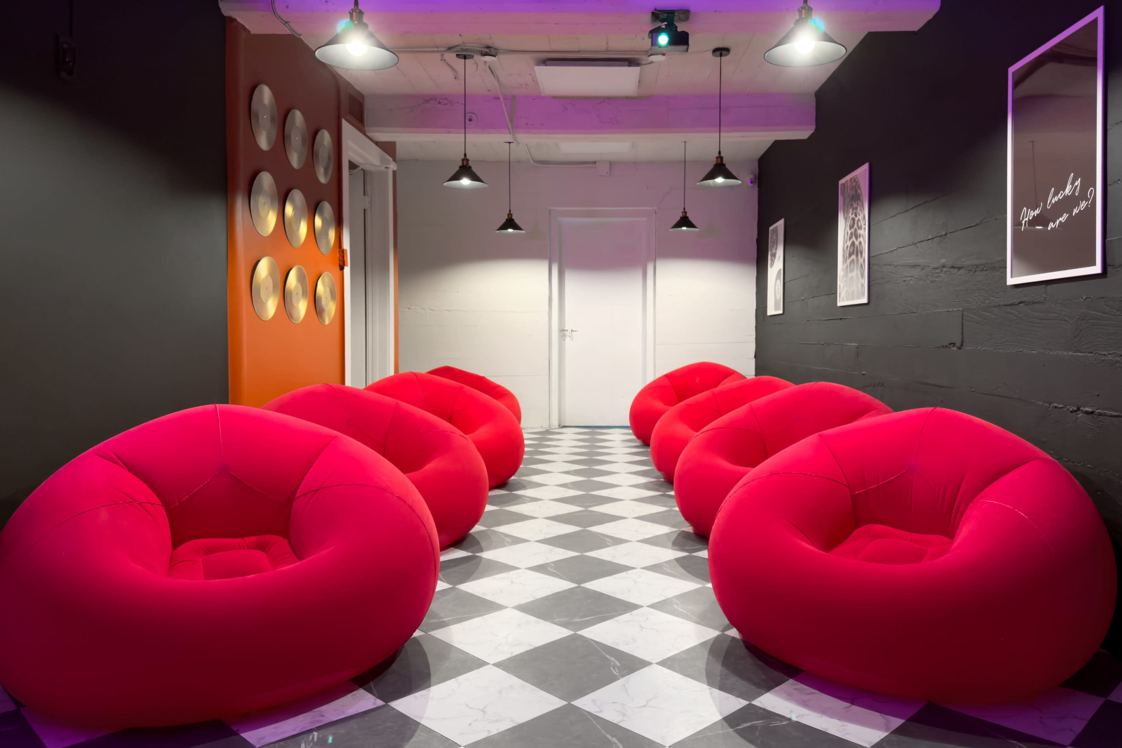 The image shows a modern hallway featuring several red bean bag chairs arranged along a checkered black and white floor.