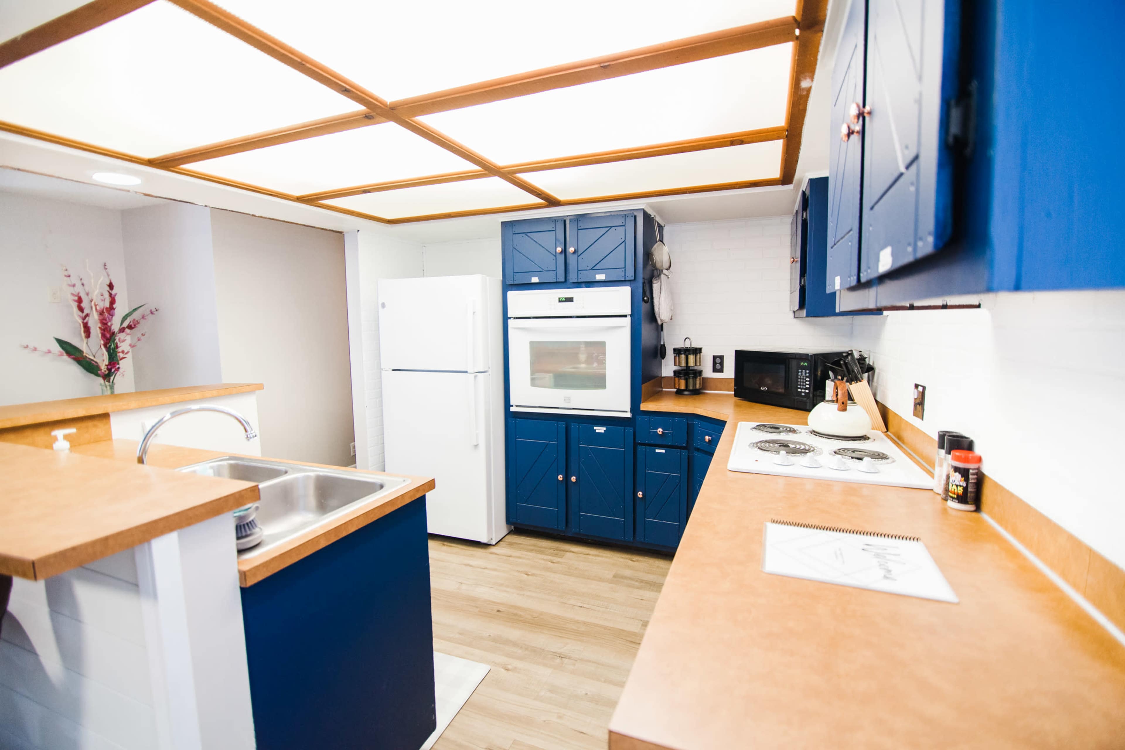 The kitchen features blue cabinetry, a white refrigerator, a built-in oven, and a countertop with a sink and stove.