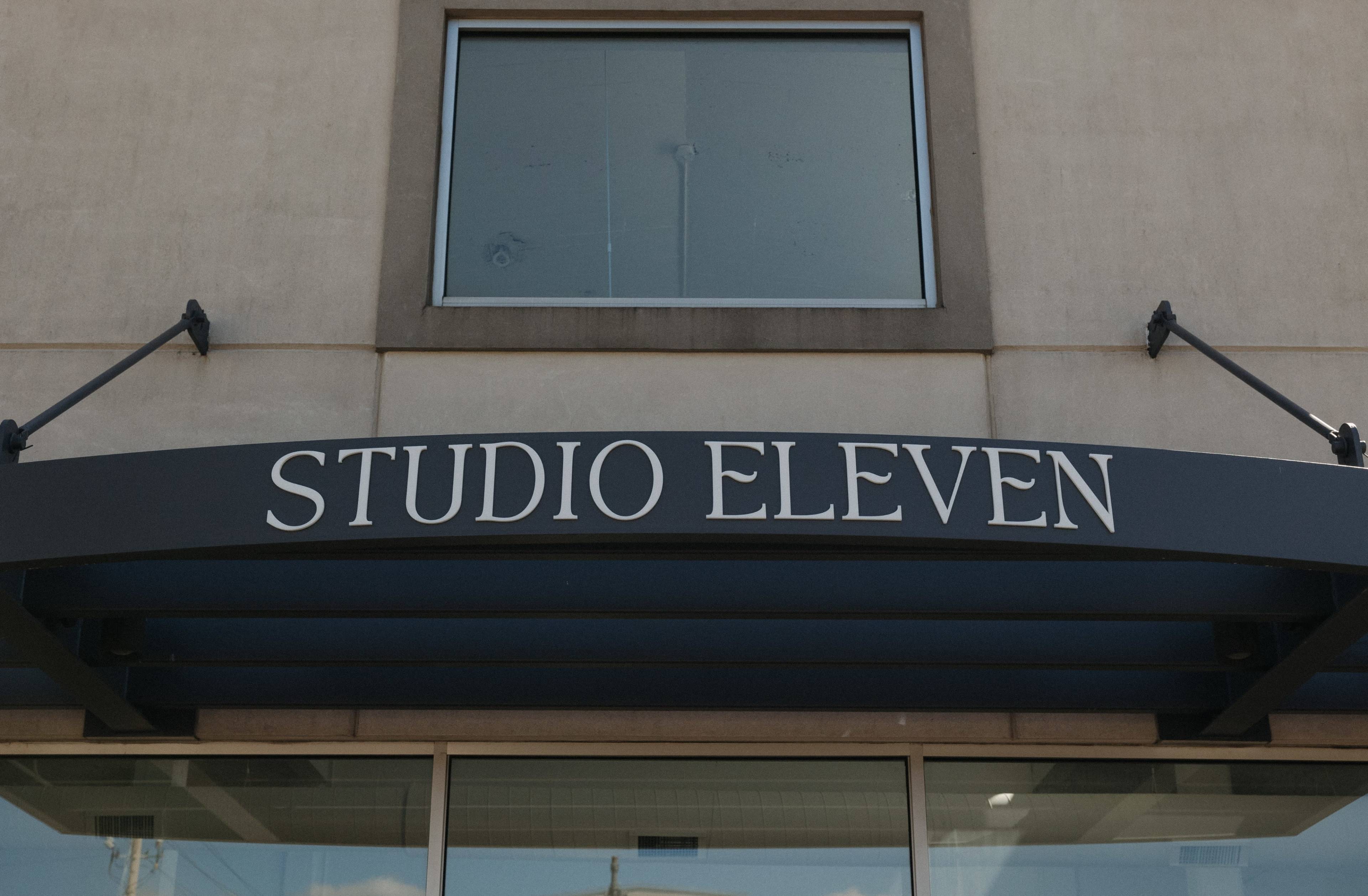 The image shows the sign for a business named "STUDIO ELEVEN" displayed above a glass entrance.