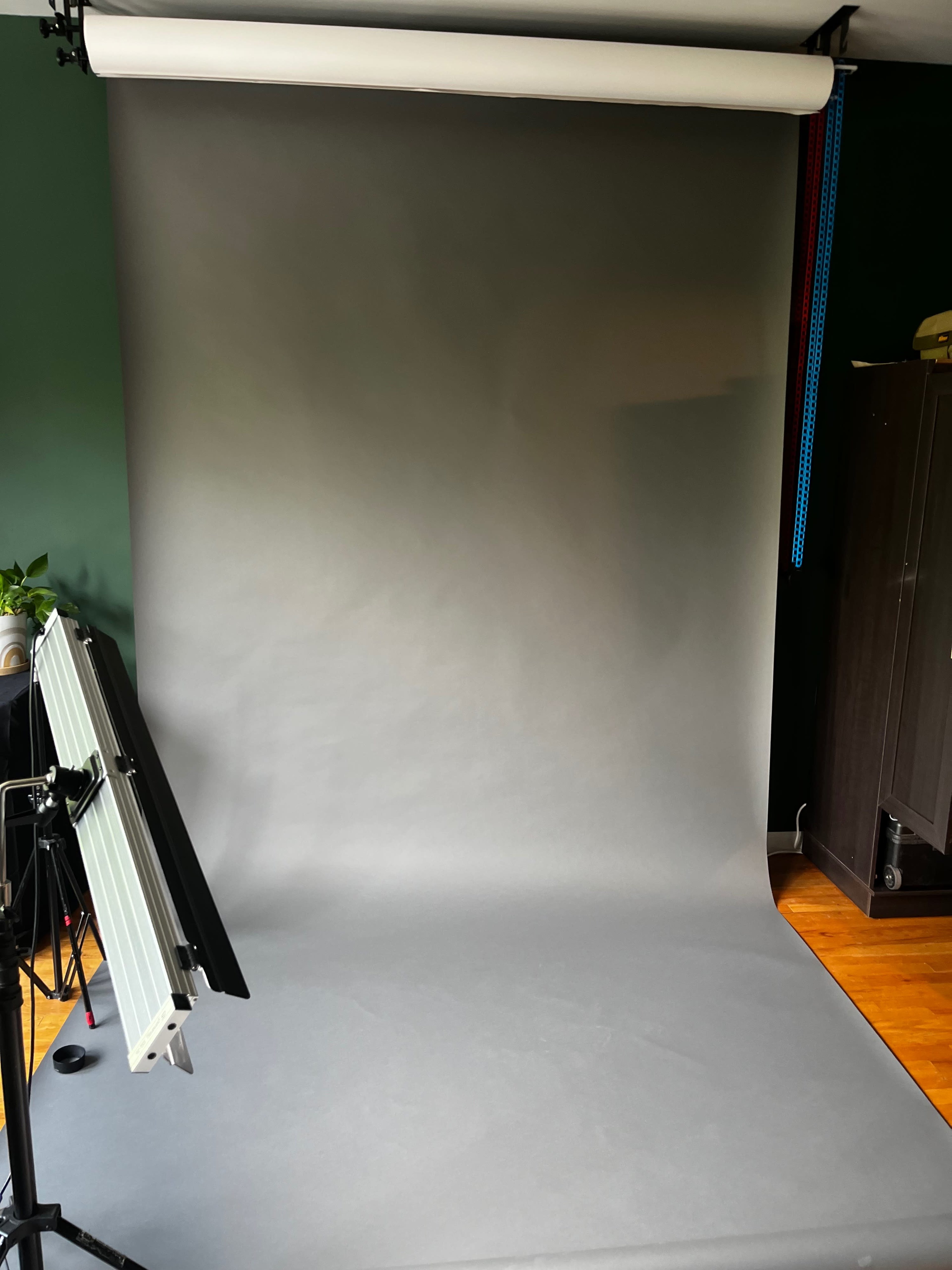 A photography studio setup featuring a gray backdrop and equipment on the left.