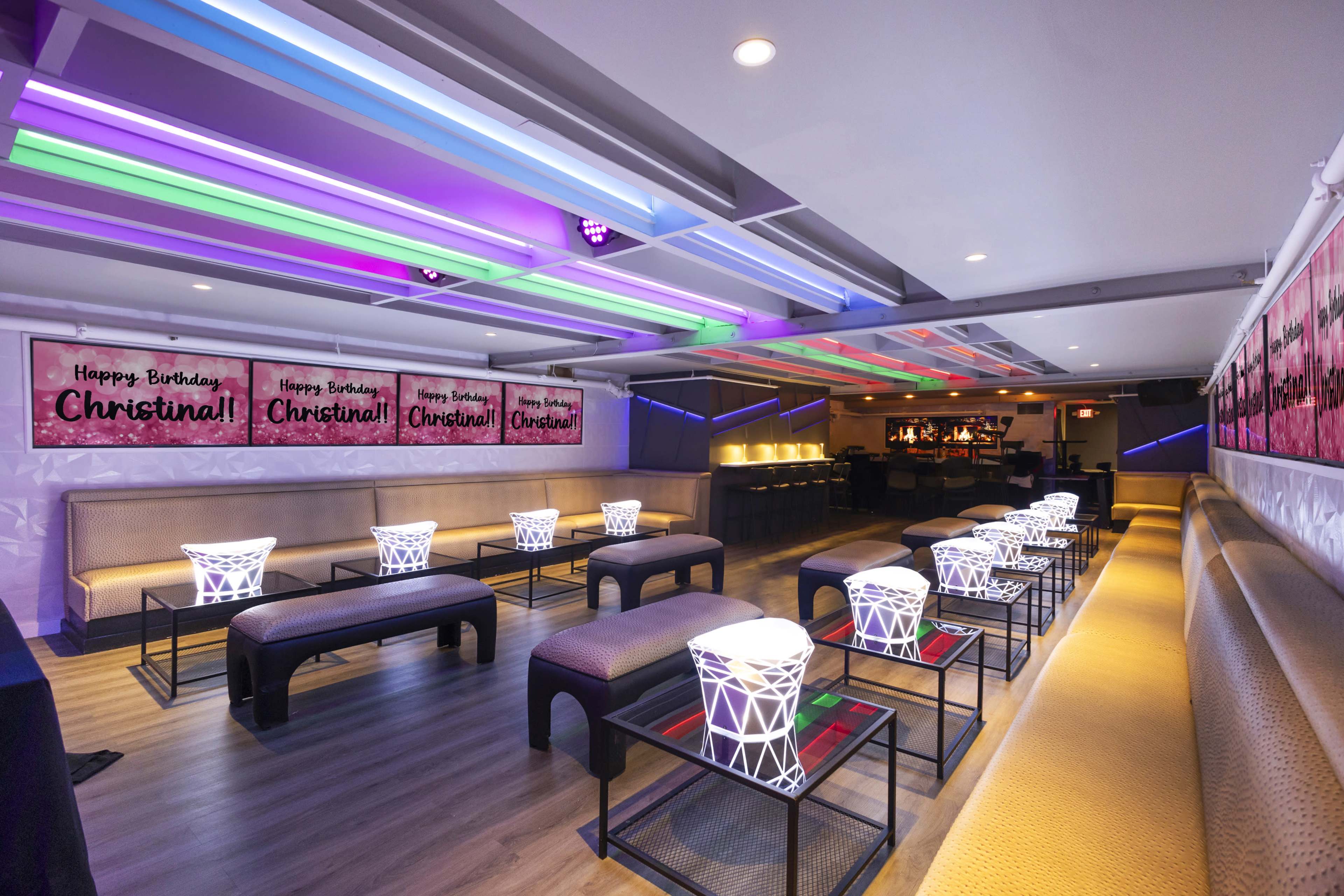The image shows a vibrant birthday celebration venue decorated with colorful lights and banners that read "Happy Birthday, Christina!"