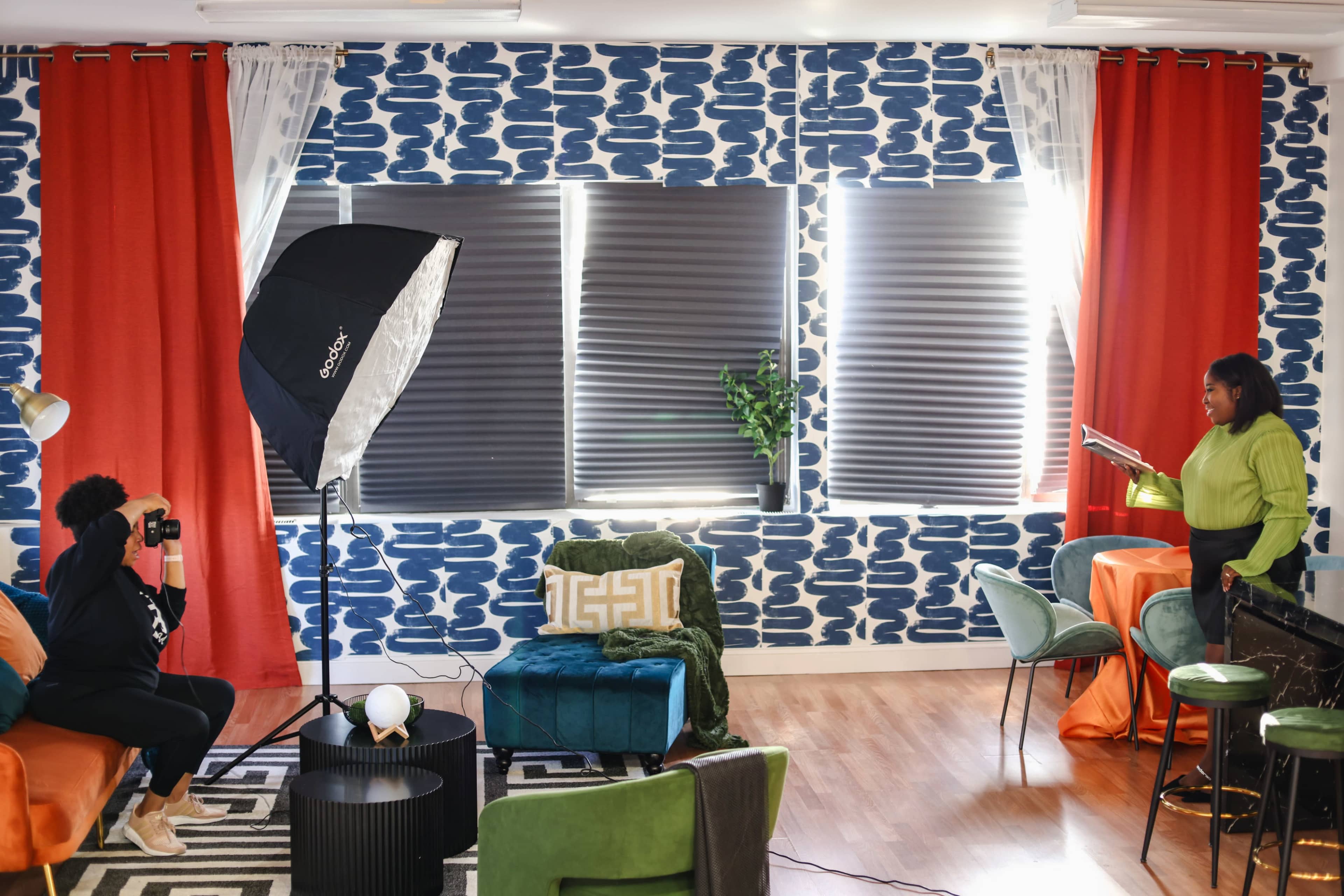 A photographer captures a subject in a brightly decorated room featuring patterned walls and various seating arrangements.