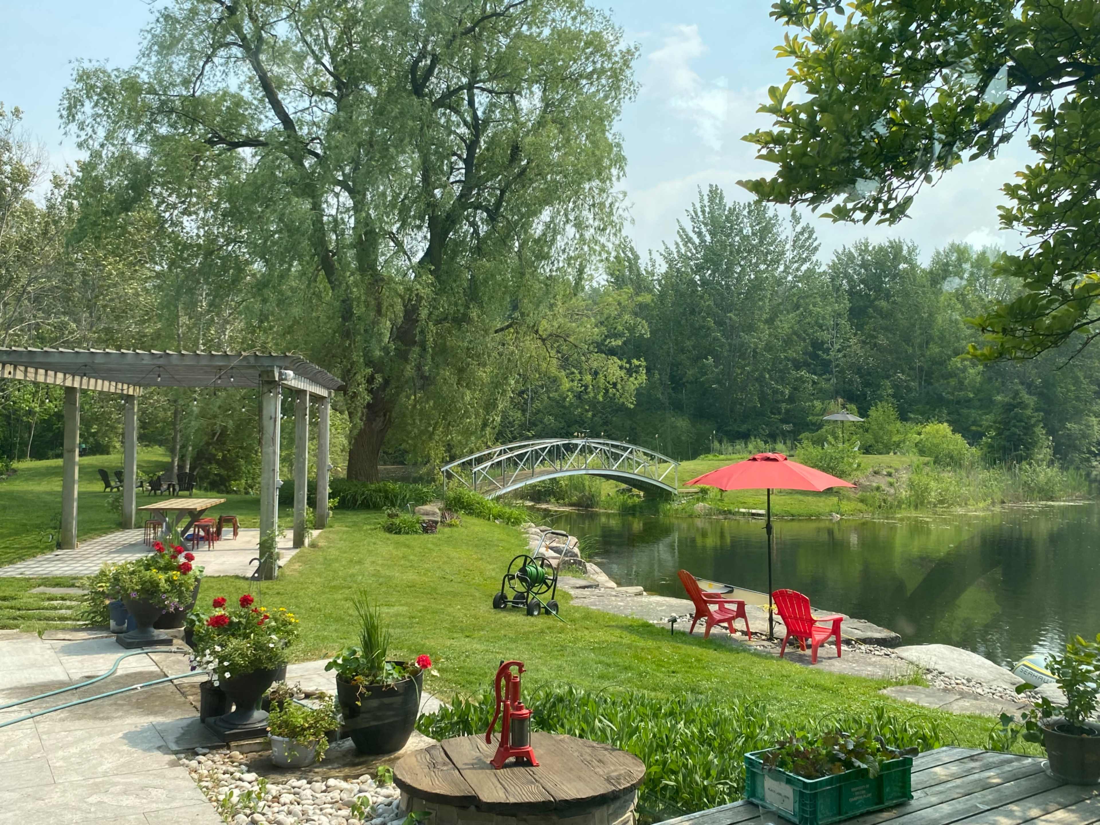 A wooden bridge arches over a calm body of water, surrounded by landscaped gardens and outdoor seating areas.