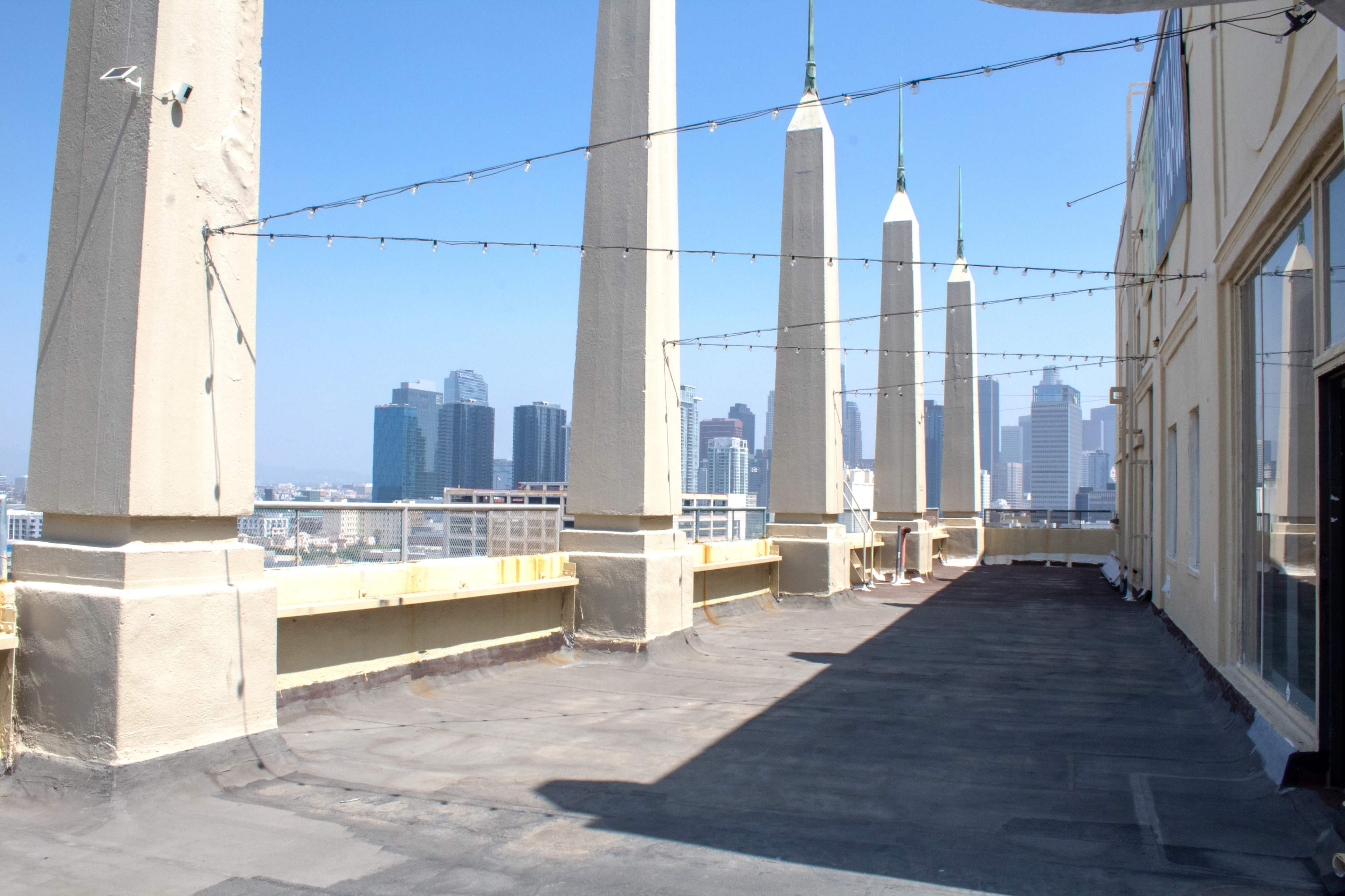 The image shows a flat rooftop with several tall, pointed structures and a skyline of skyscrapers in the background.