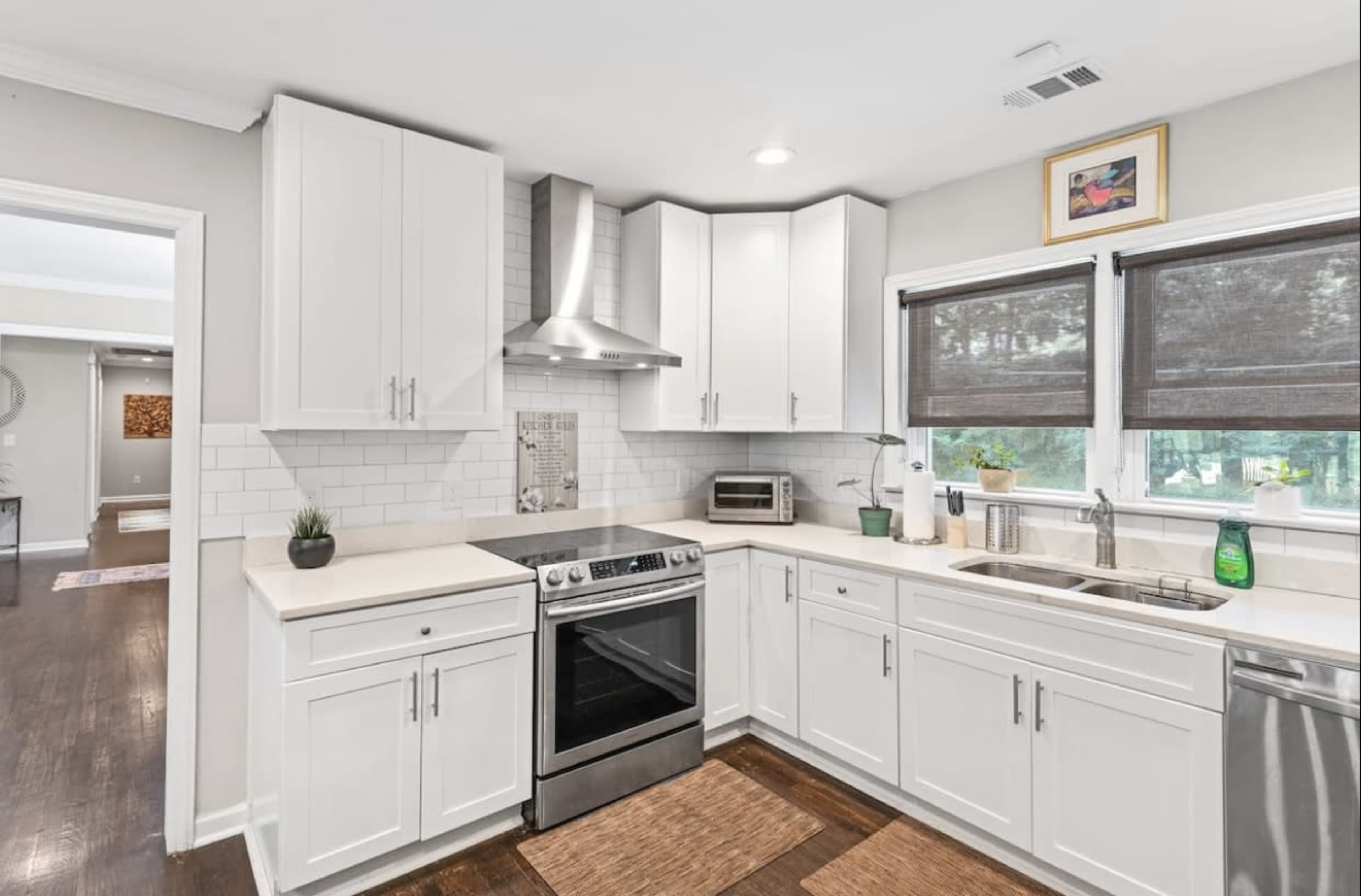 A modern kitchen with white cabinetry, stainless steel appliances, and a tile backsplash.