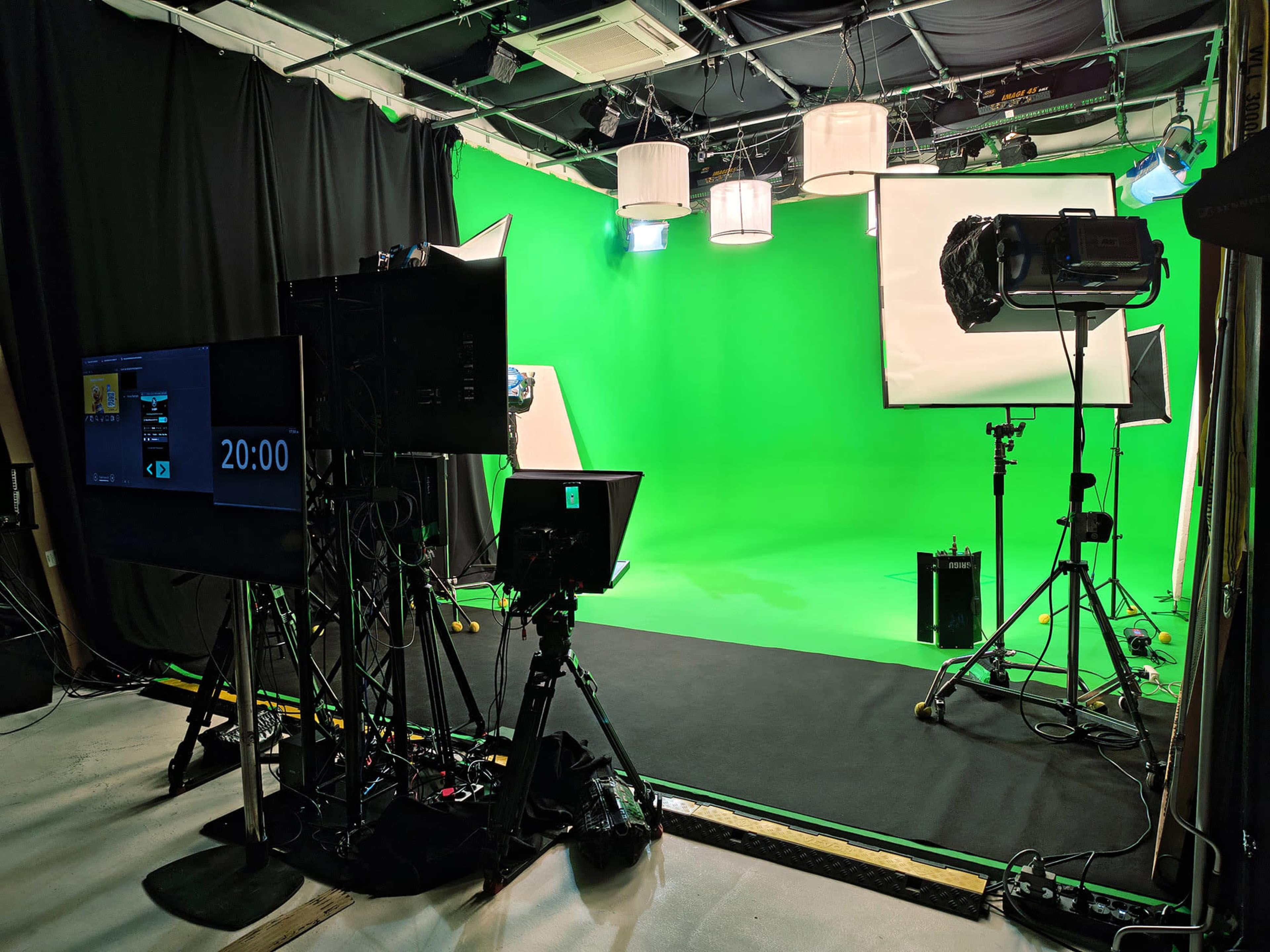 The image shows a green screen studio equipped with lighting, cameras, and a countdown timer.