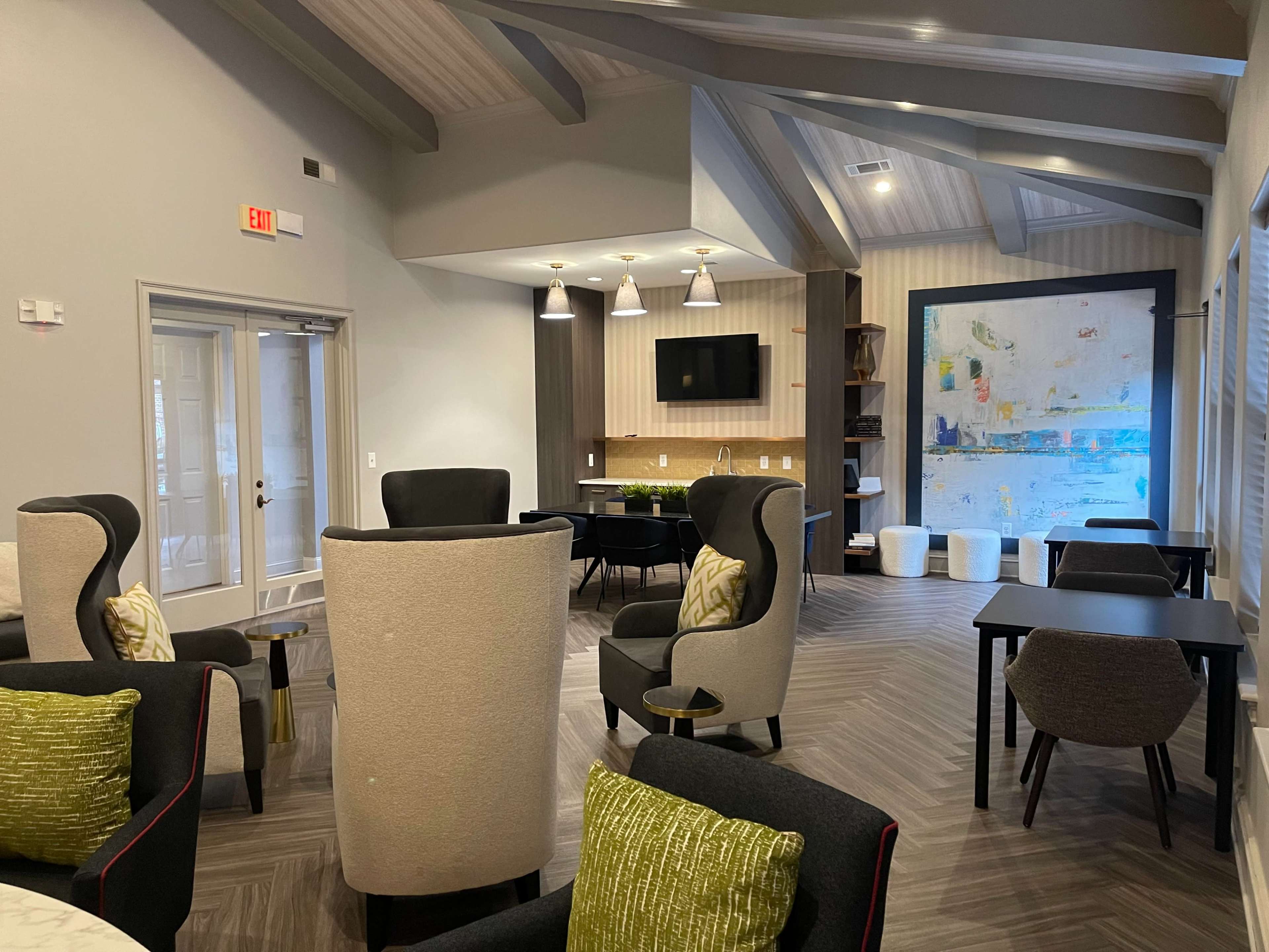 A modern lounge area featuring comfortable seating, a television, and a decorative wall with abstract artwork.