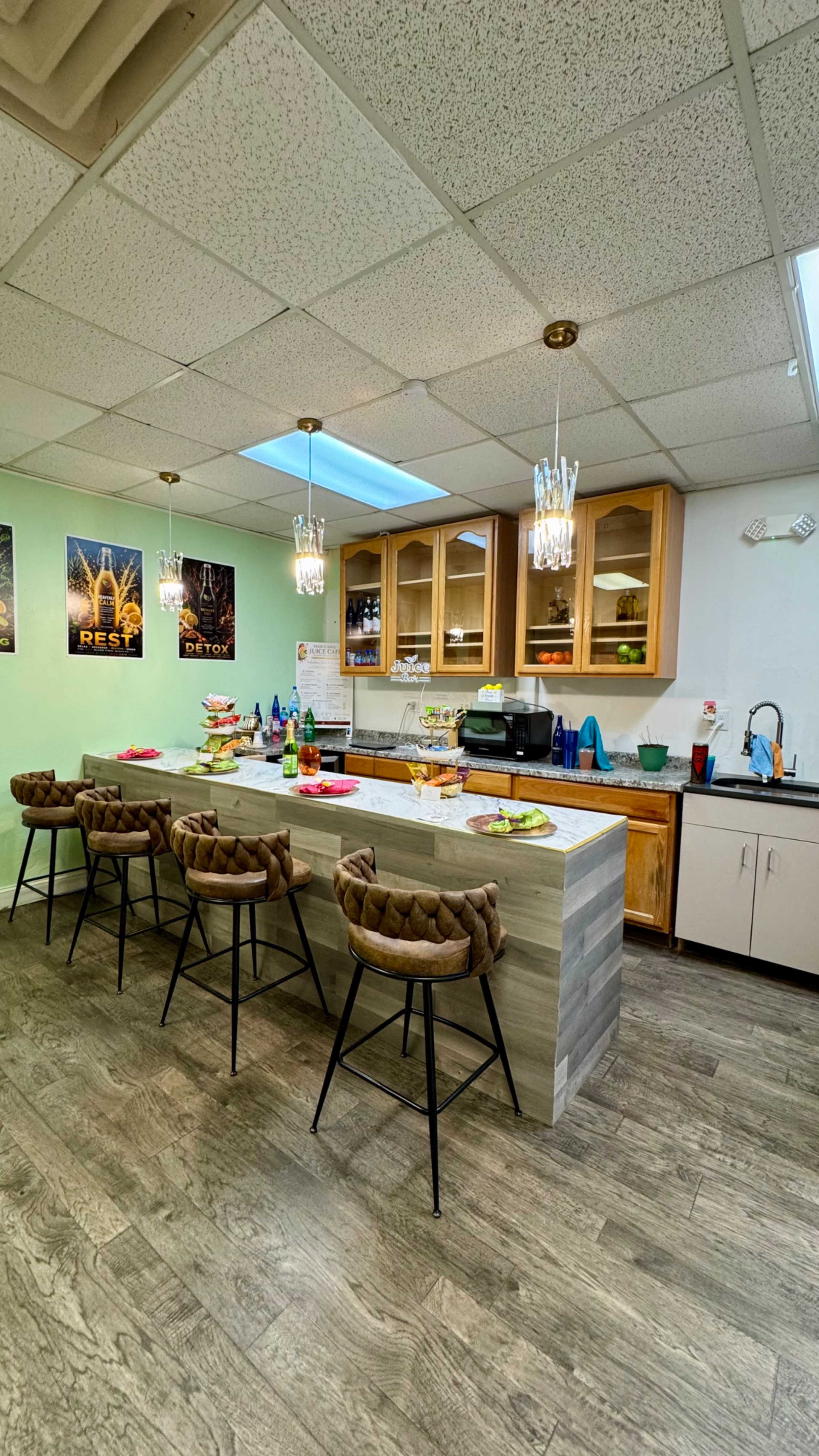 The image shows a modern kitchen with a large island, bar stools, and a variety of food and drinks arranged on the counter.