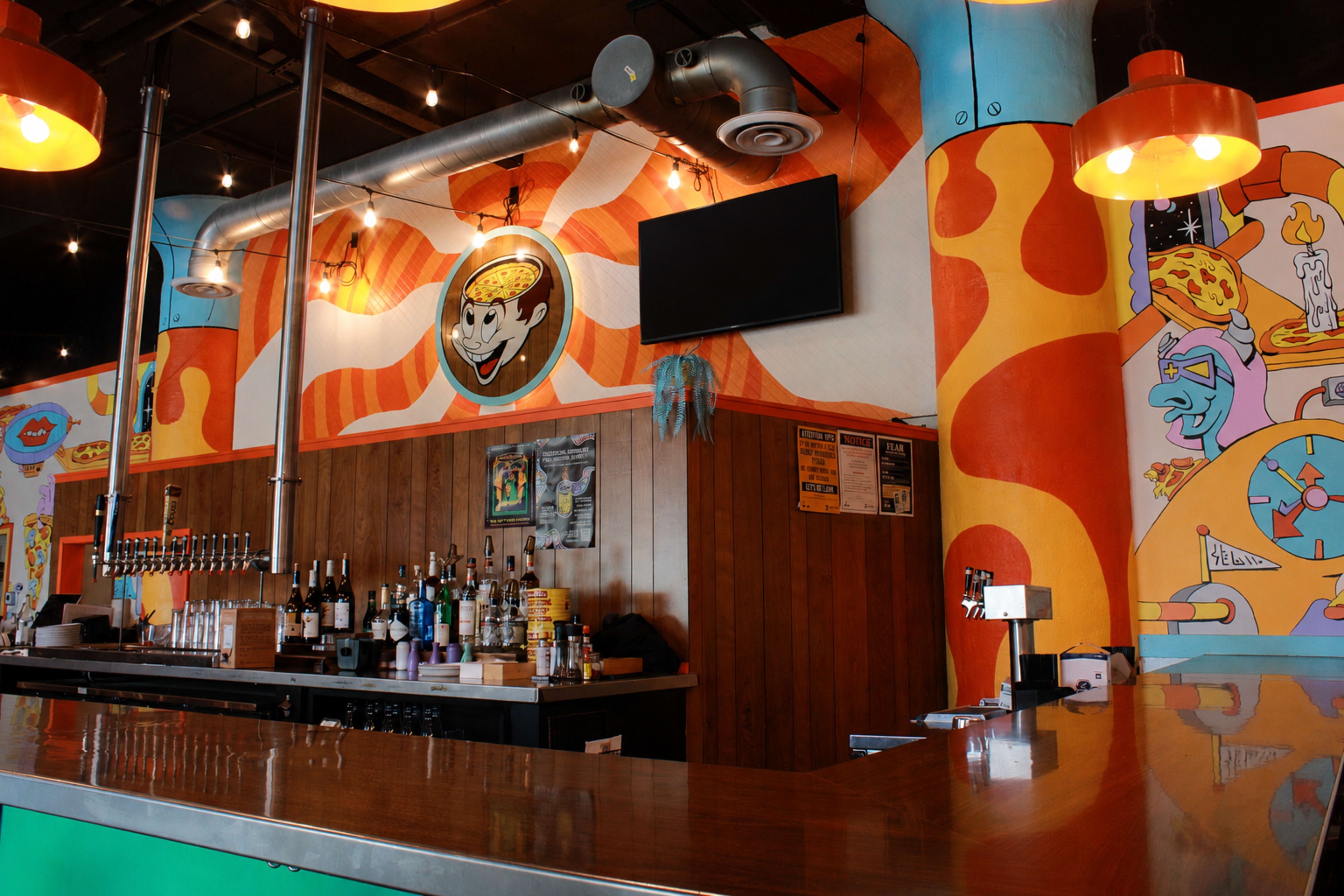 The image shows a vibrant bar area with colorful mural art on the walls and a polished wooden counter.