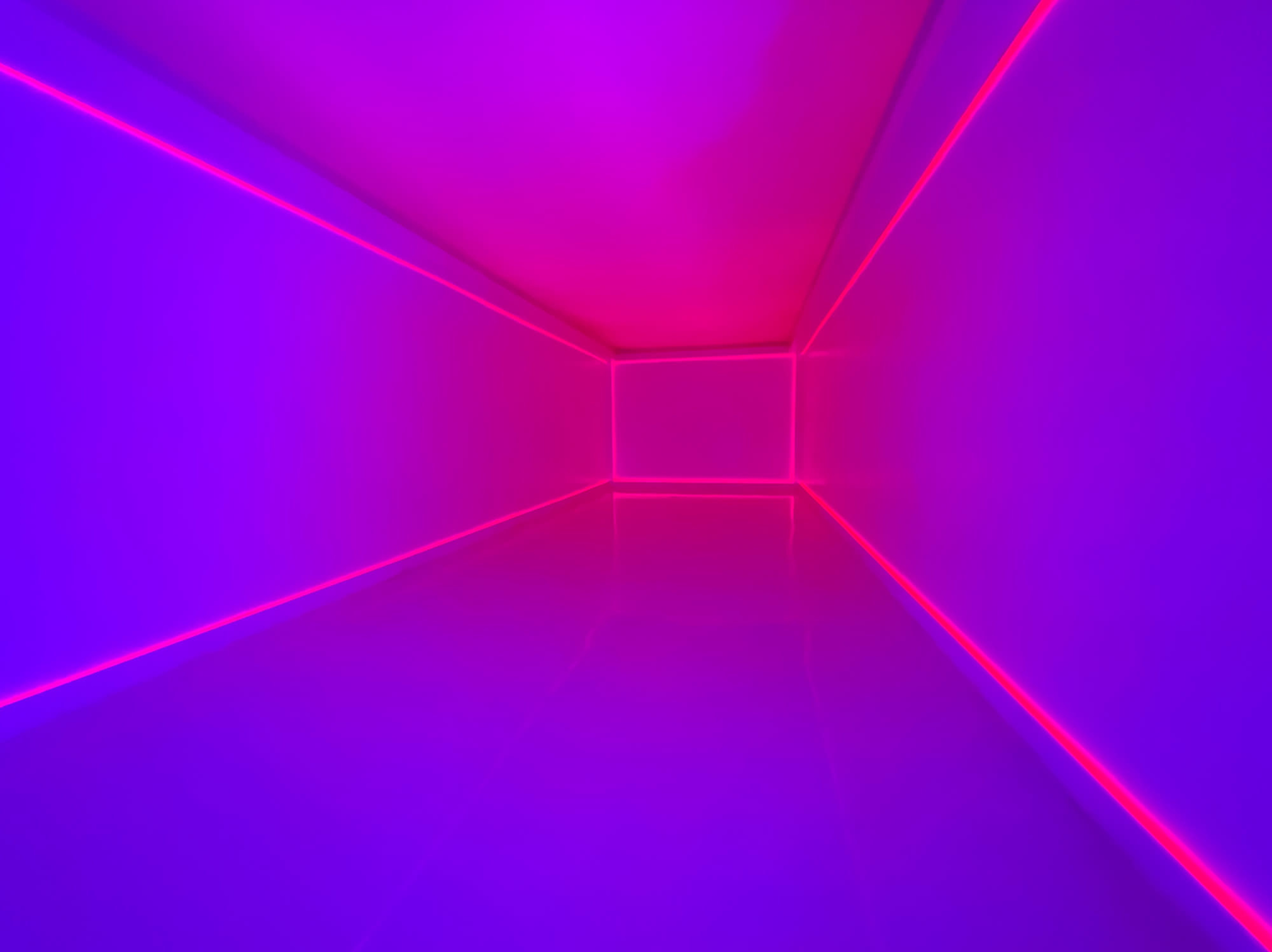 A futuristic, empty room illuminated by purple and pink neon lights along the walls and floor.