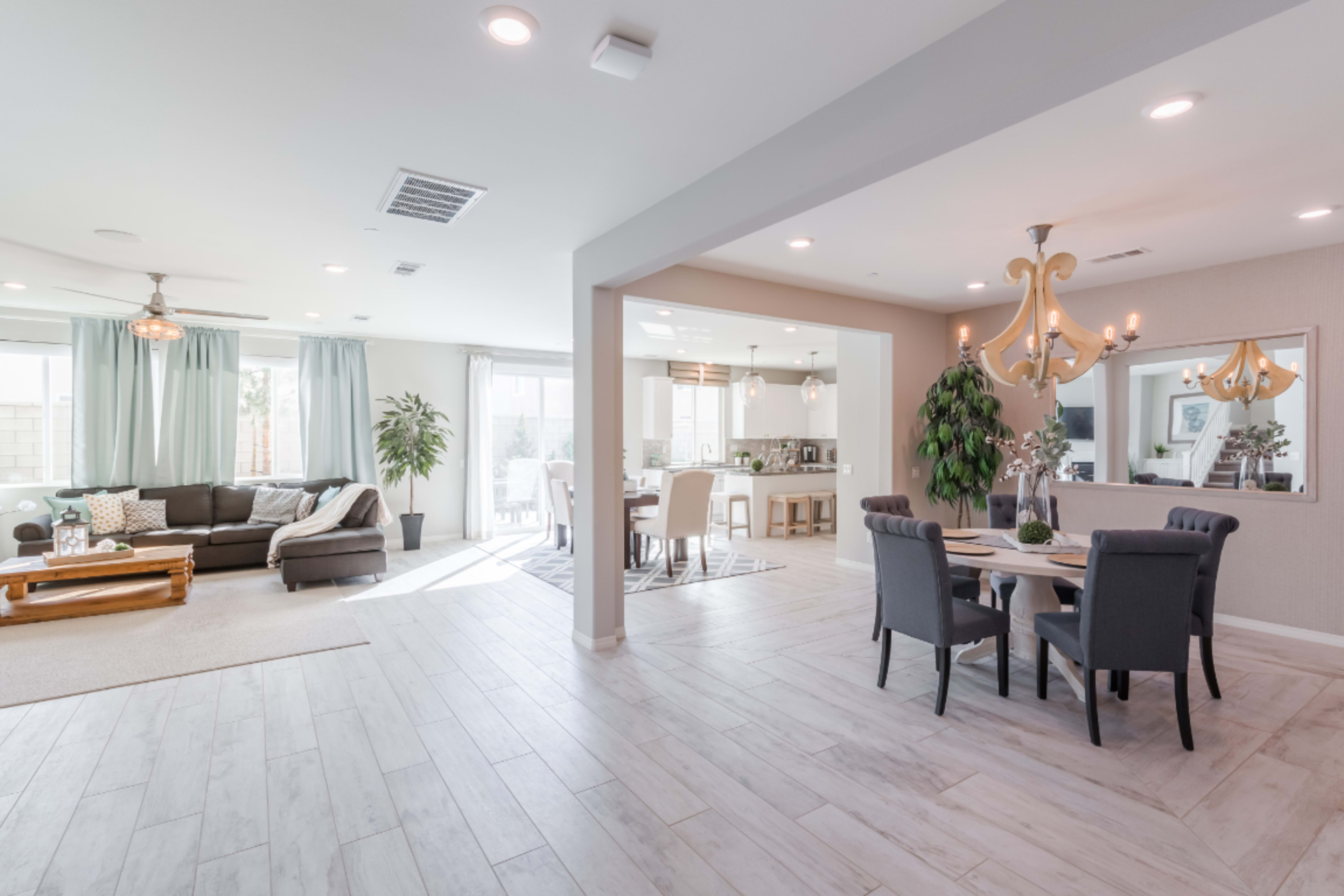 A modern open-concept living space with a seating area, dining table, and kitchen visible in the background.